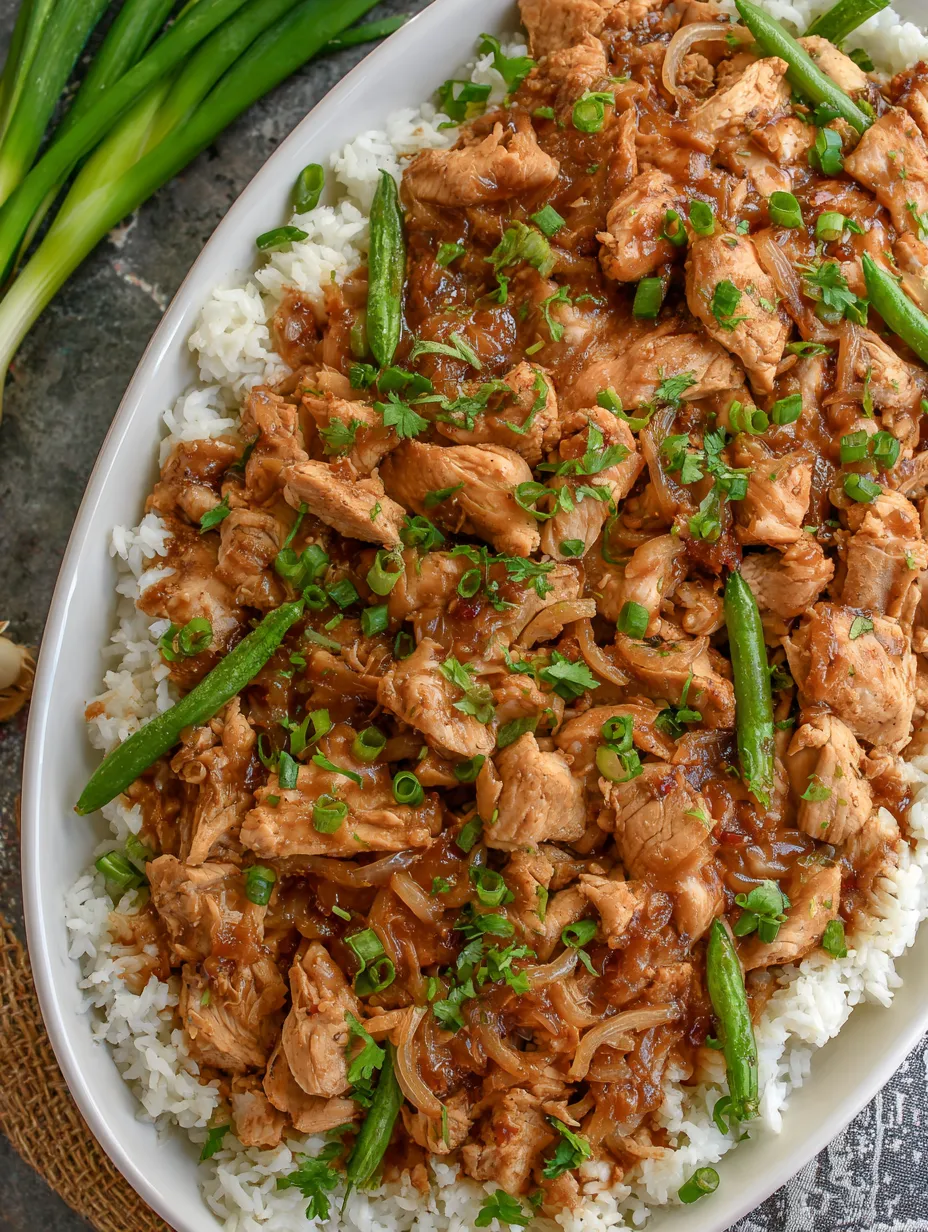 Ein weißer Teller mit einer Mischung aus Rice, Chicken und Zwiebeln.