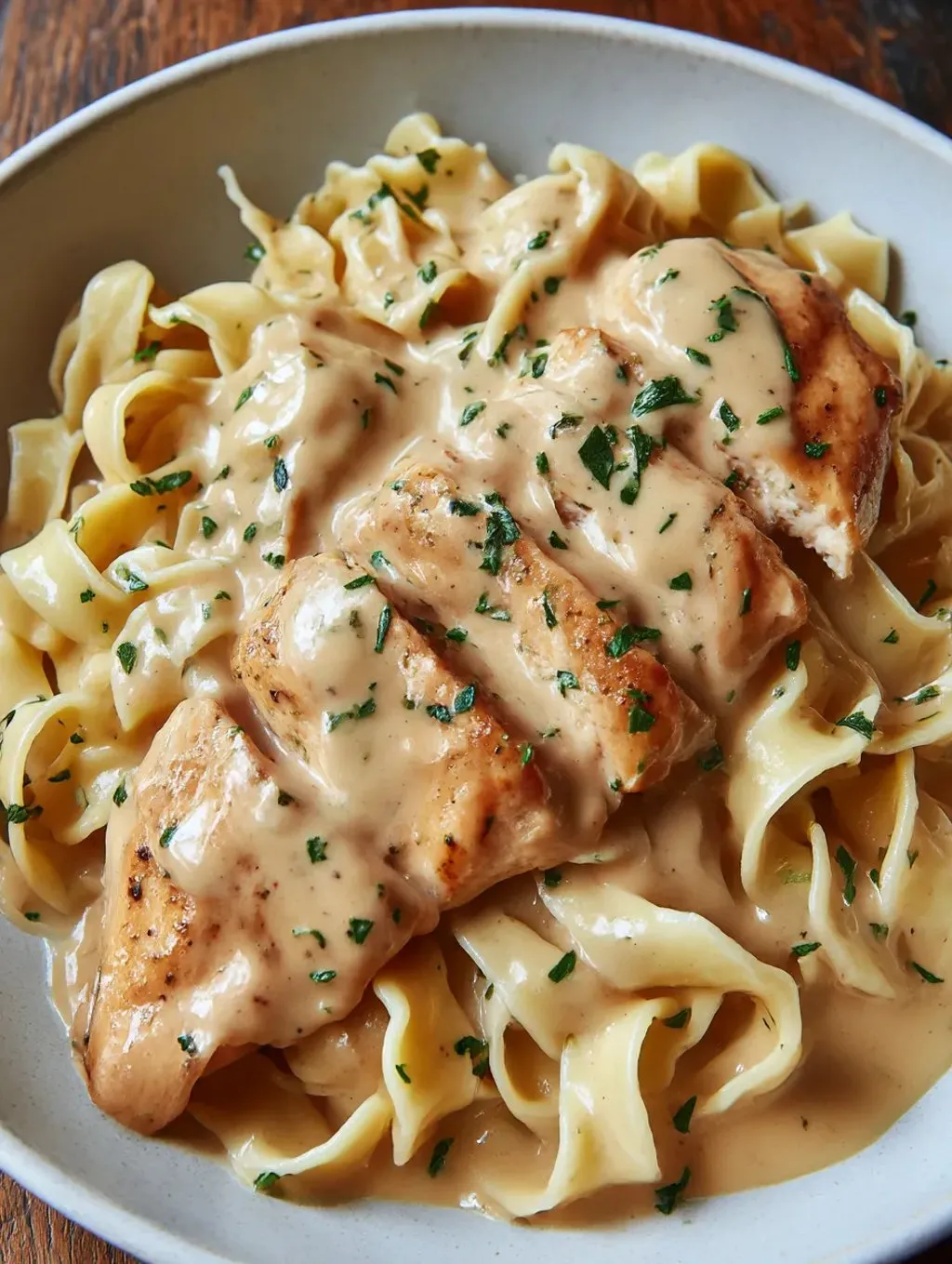 Ein Bild von einer Tasse mit Pasta, Chicken und Sauce.