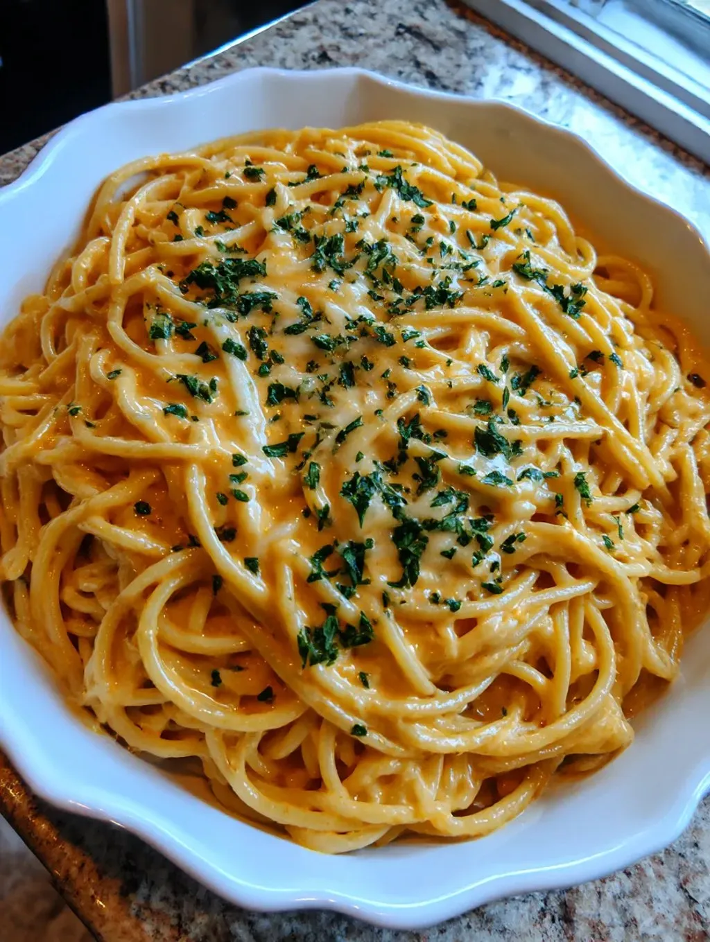 Ein weißer Teller mit einer Portion von Cheesy Garlic Parmesan Spaghetti.