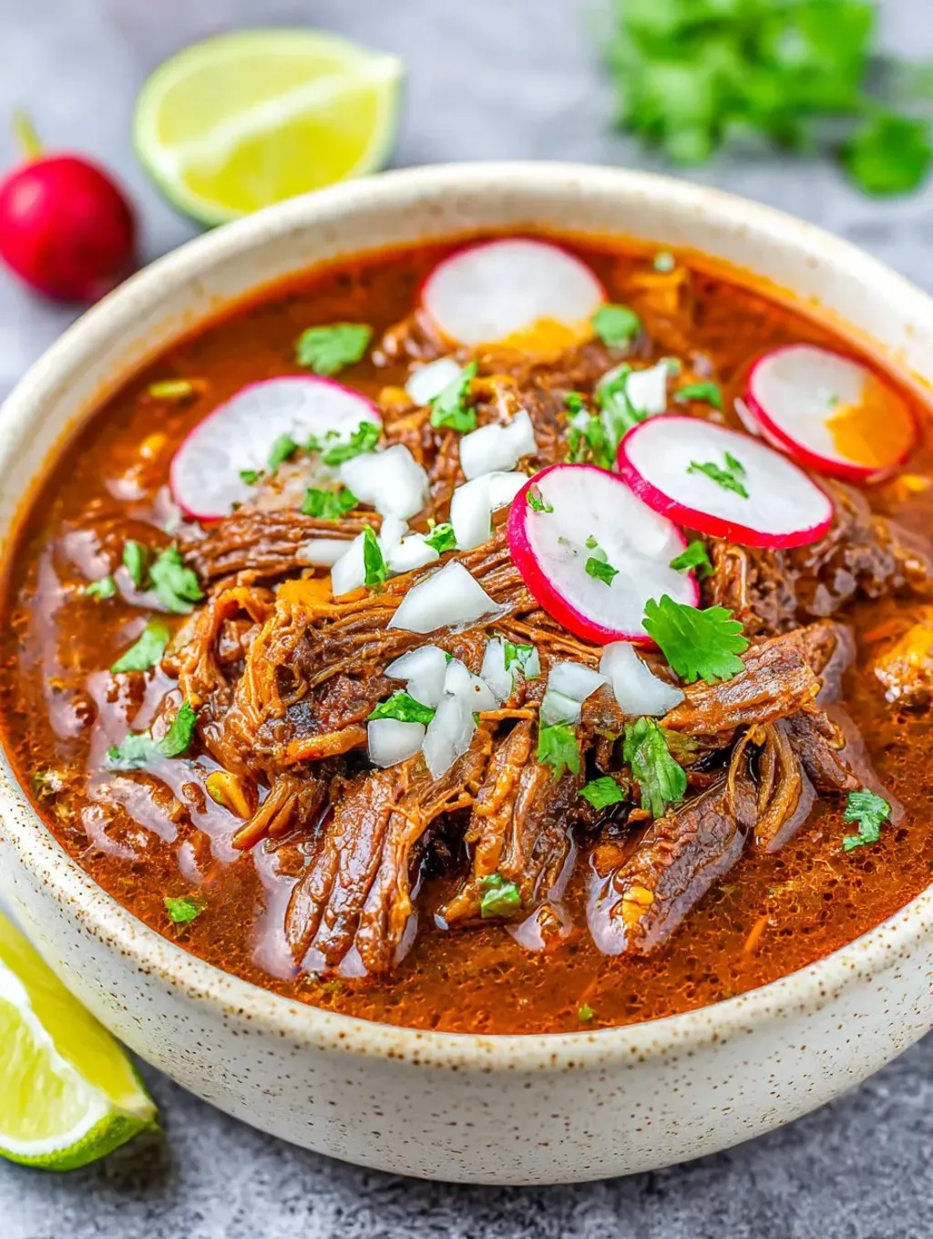 Ein Schalen mit Birria, einer mexikanischen Beef-Gericht, das mit Tomaten, Knoblauch und anderen Zutaten zubereitet wurde.