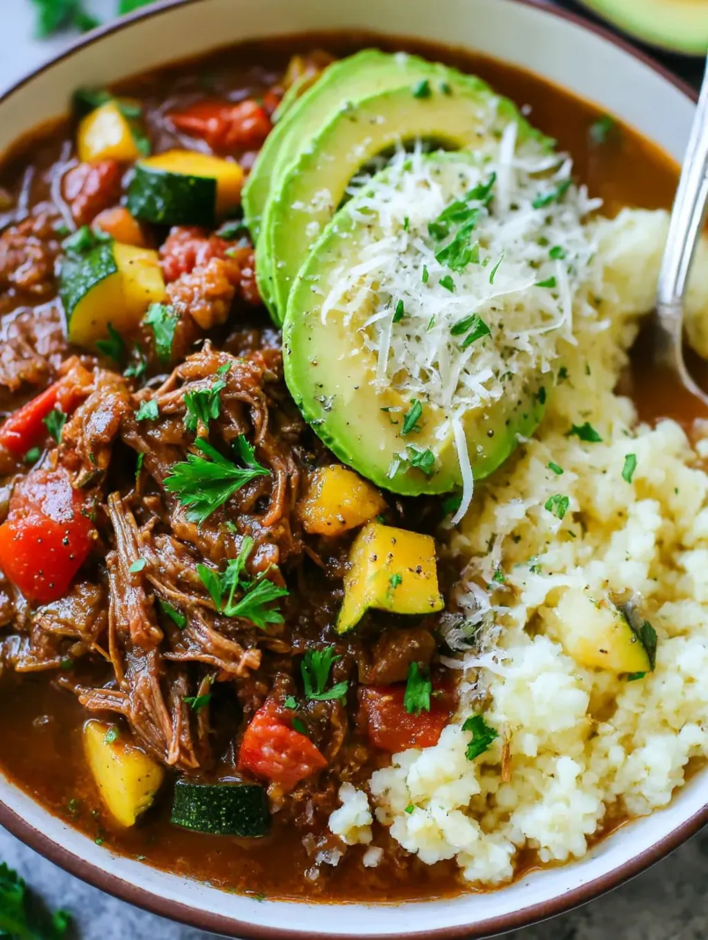 Ein Bild von einer Beef-Casserole mit verschiedenen Zutaten wie Avocado, Zucchini, Kartoffeln, Zwiebeln und Tomaten.