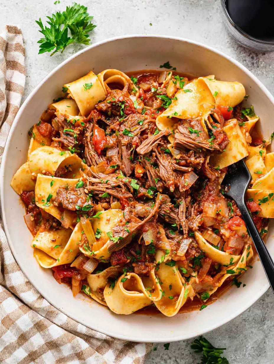 Ein weißer Teller mit einer Mischung aus Pasta, Fleisch und Gemüse.