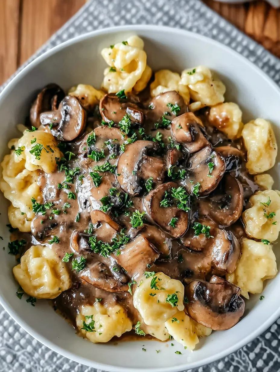 Ein weißer Teller mit macaroni und mushrooms.