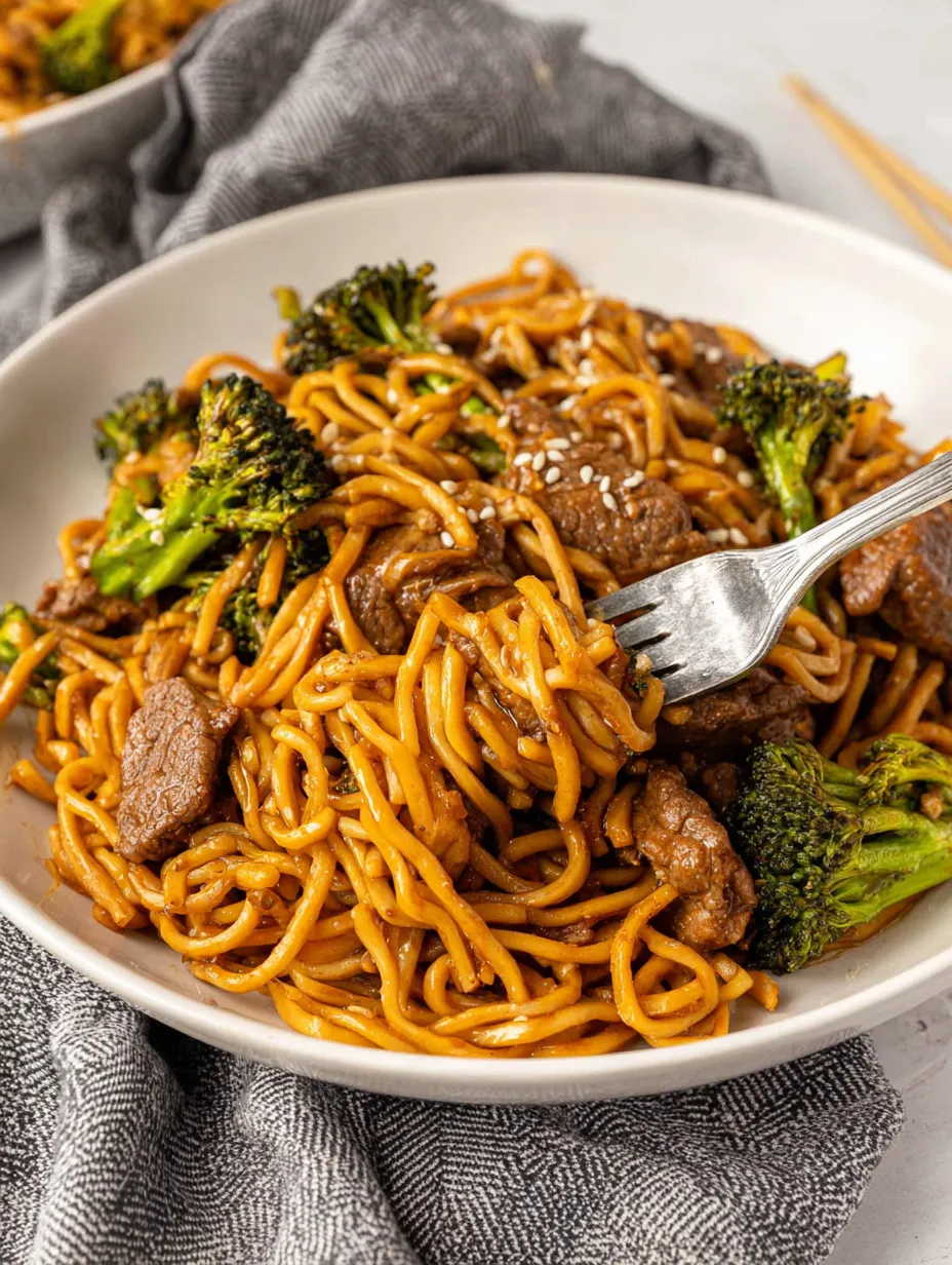 A plate of noodles with meat and broccoli.