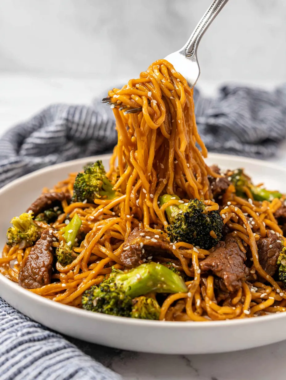 A plate of noodles with broccoli and meat.