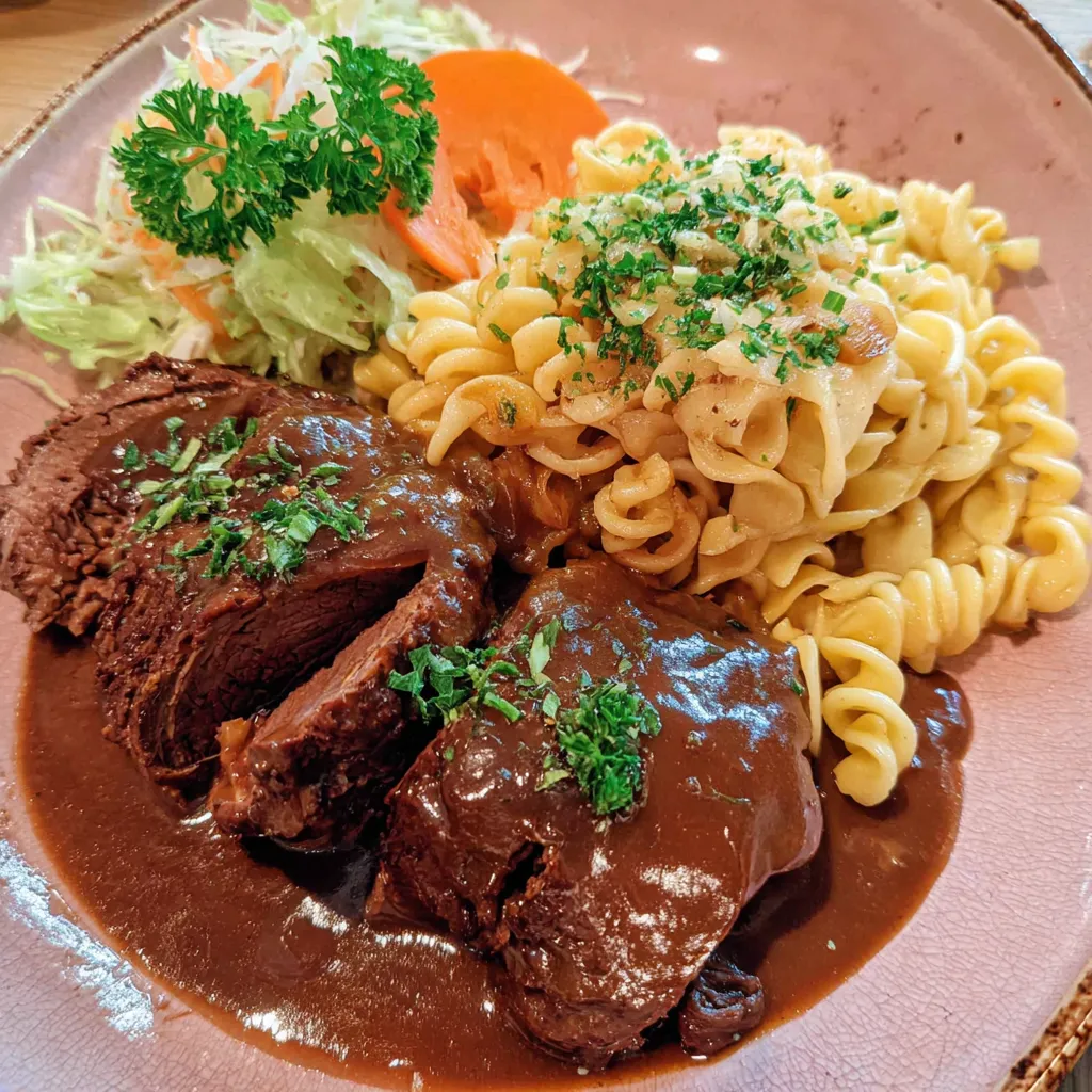 Ein Plate mit gegrilltem Fleisch, Pasta, Salat und Sauce.