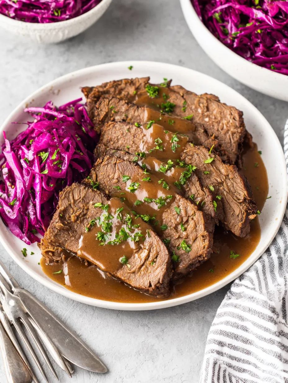 Ein weißer Teller mit rohem Fleisch, das mit Sauce bedeckt ist.