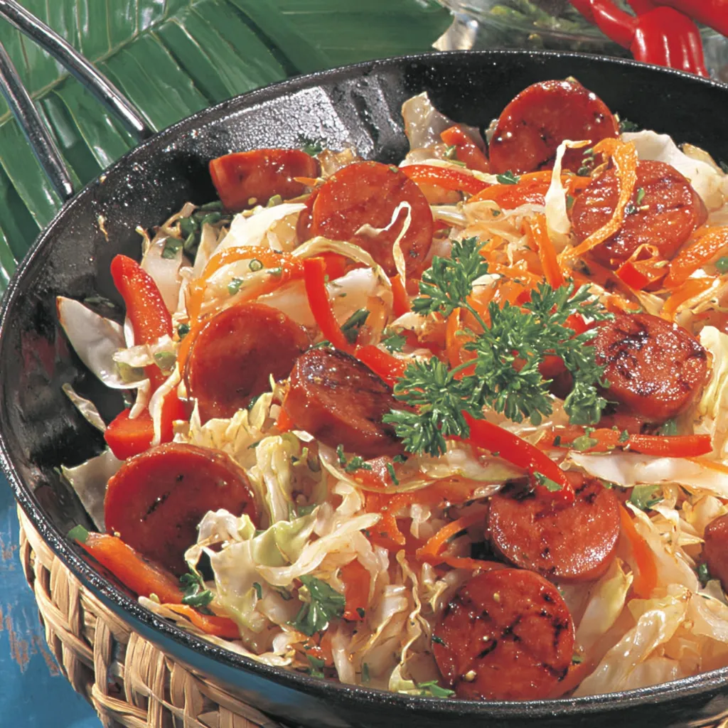 Ein schwarzes, leeres Wok mit einer Schüssel voller Gemüse und Wurst.