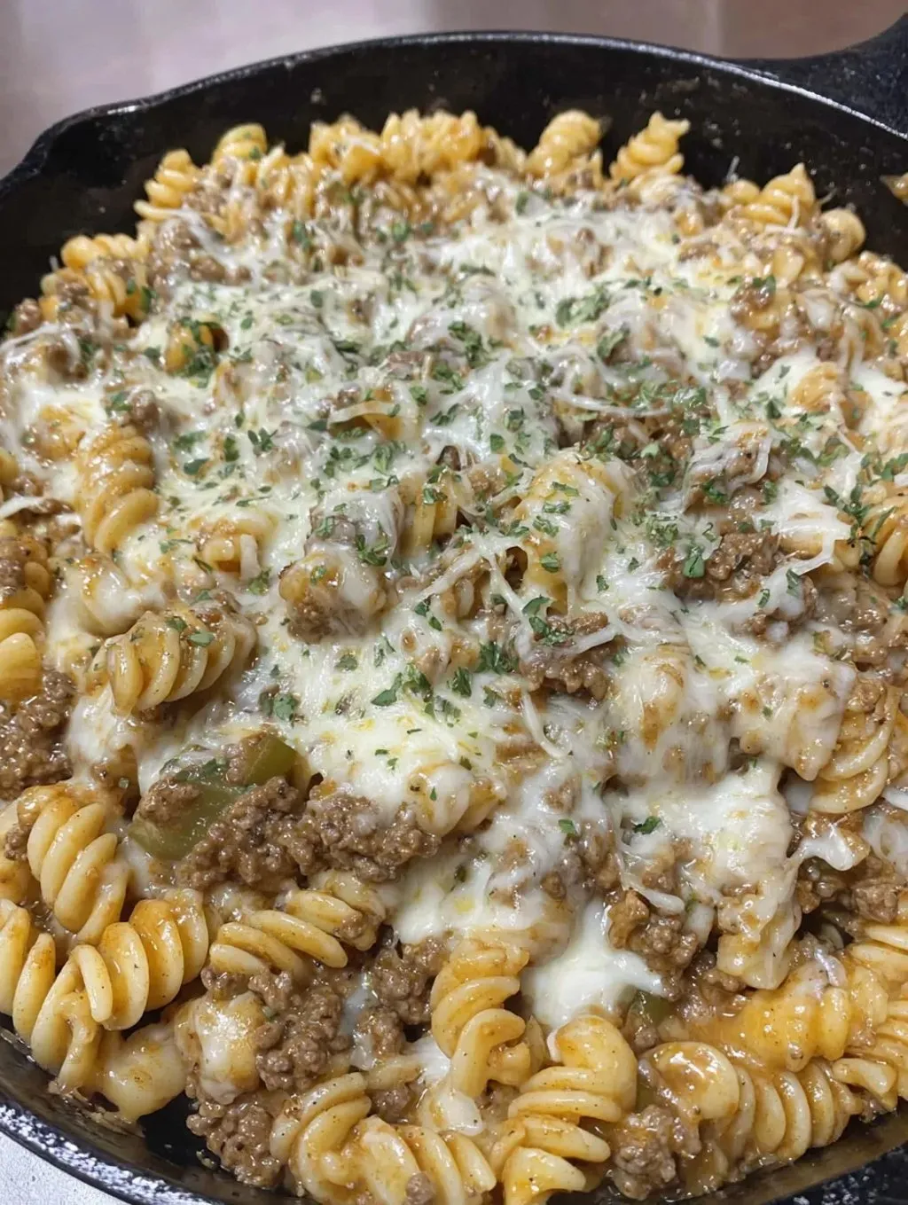 Eine Schüssel mit Penne-Nudelsalat, der mit Käse, Zwiebeln und Rindfleisch garniert ist.