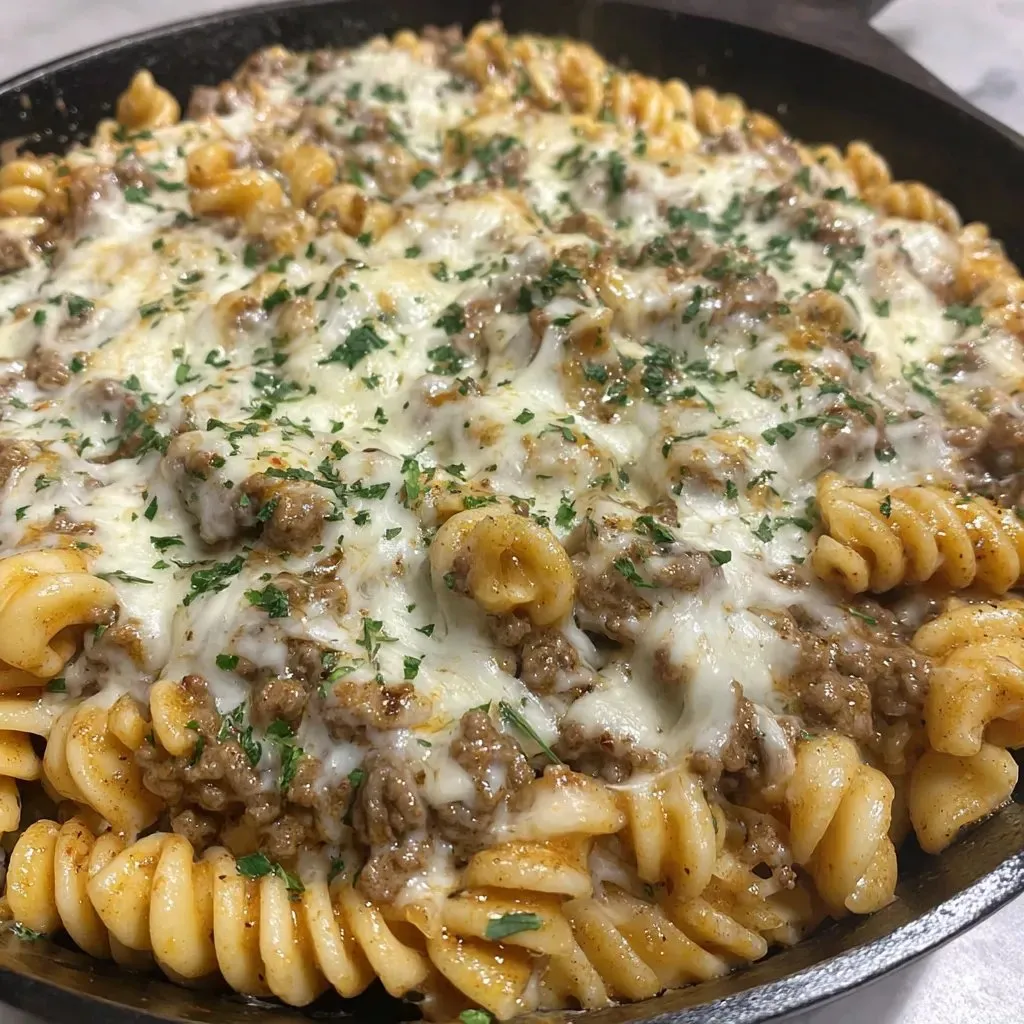 Eine Schüssel mit Penne-Nudelsalat, der mit Käse und gerösteten Zwiebeln garniert ist.