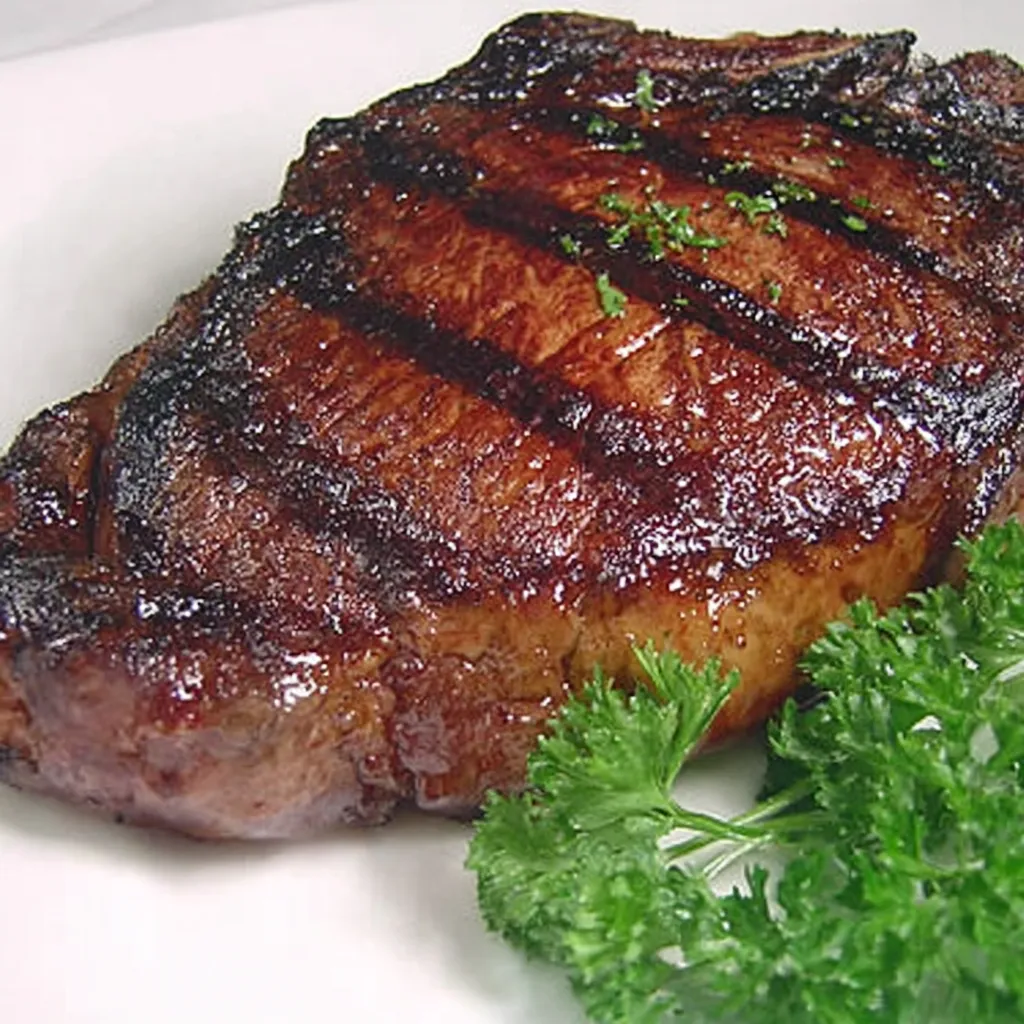 Eine Porterhouse-Steak auf einem weißen Teller, garniert mit frischem Parsley.