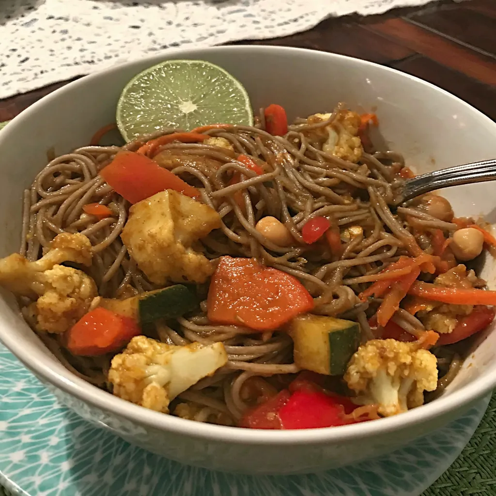 Ein weißer Teller mit einer Mischung aus Nudeln, Gemüse und Zwiebeln.