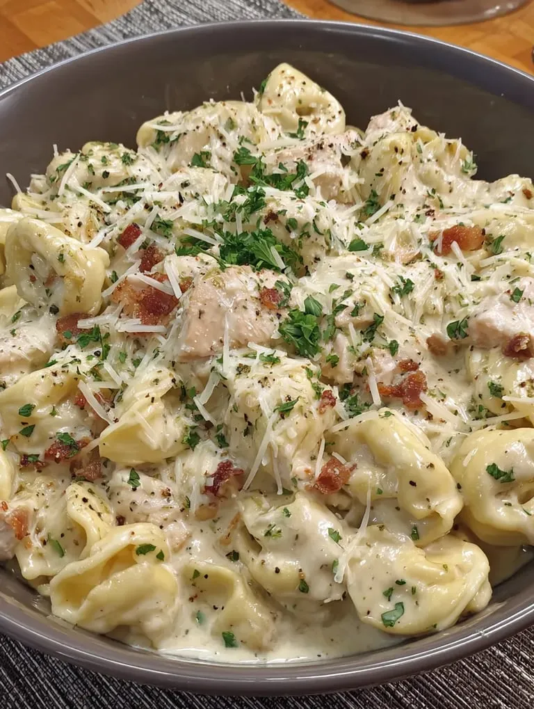 Ein Bild von einer Pasta-Garnitur, die mit Bacon, Zwiebeln und Käse garniert ist.