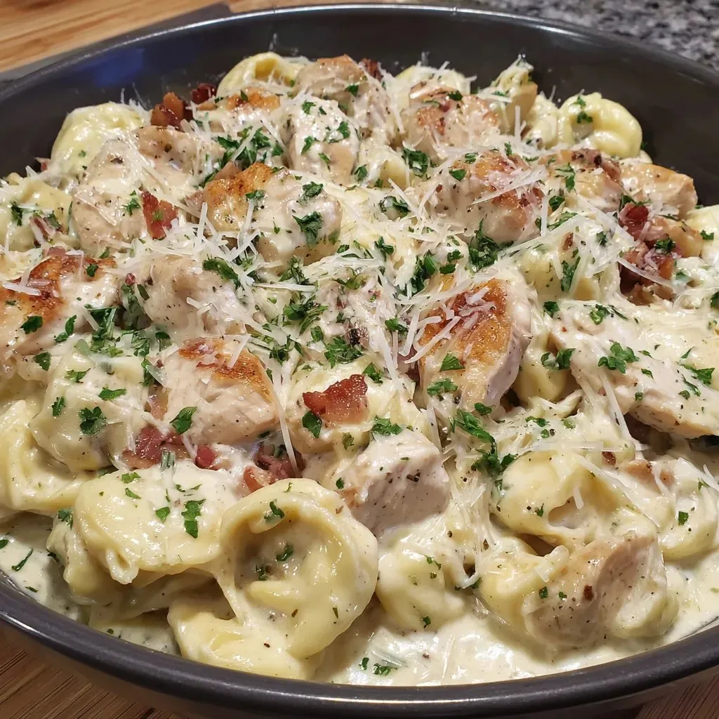 Ein großes, glänzendes, silbernes Becken mit einer Mischung aus Pasta, Chicken und Bacon.