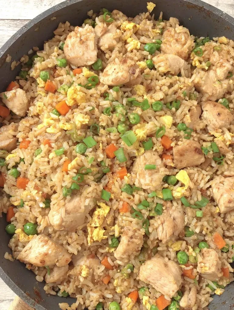 Ein Bild von einer Rice-Gerichte mit Chicken, Peas und Carrots.