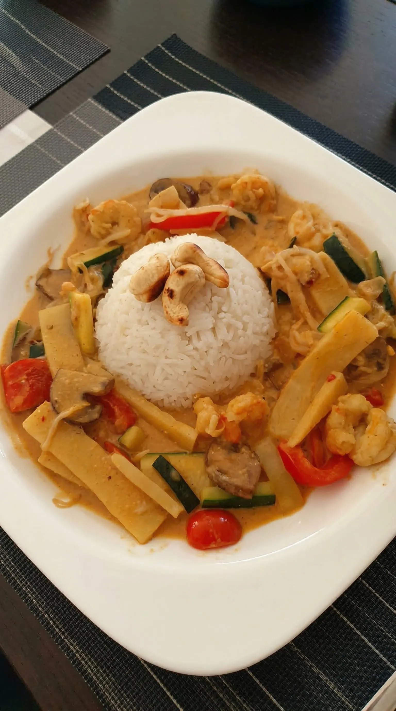 Ein Thai Curry mit Kokos und Hühnchen auf einem weißen Teller.