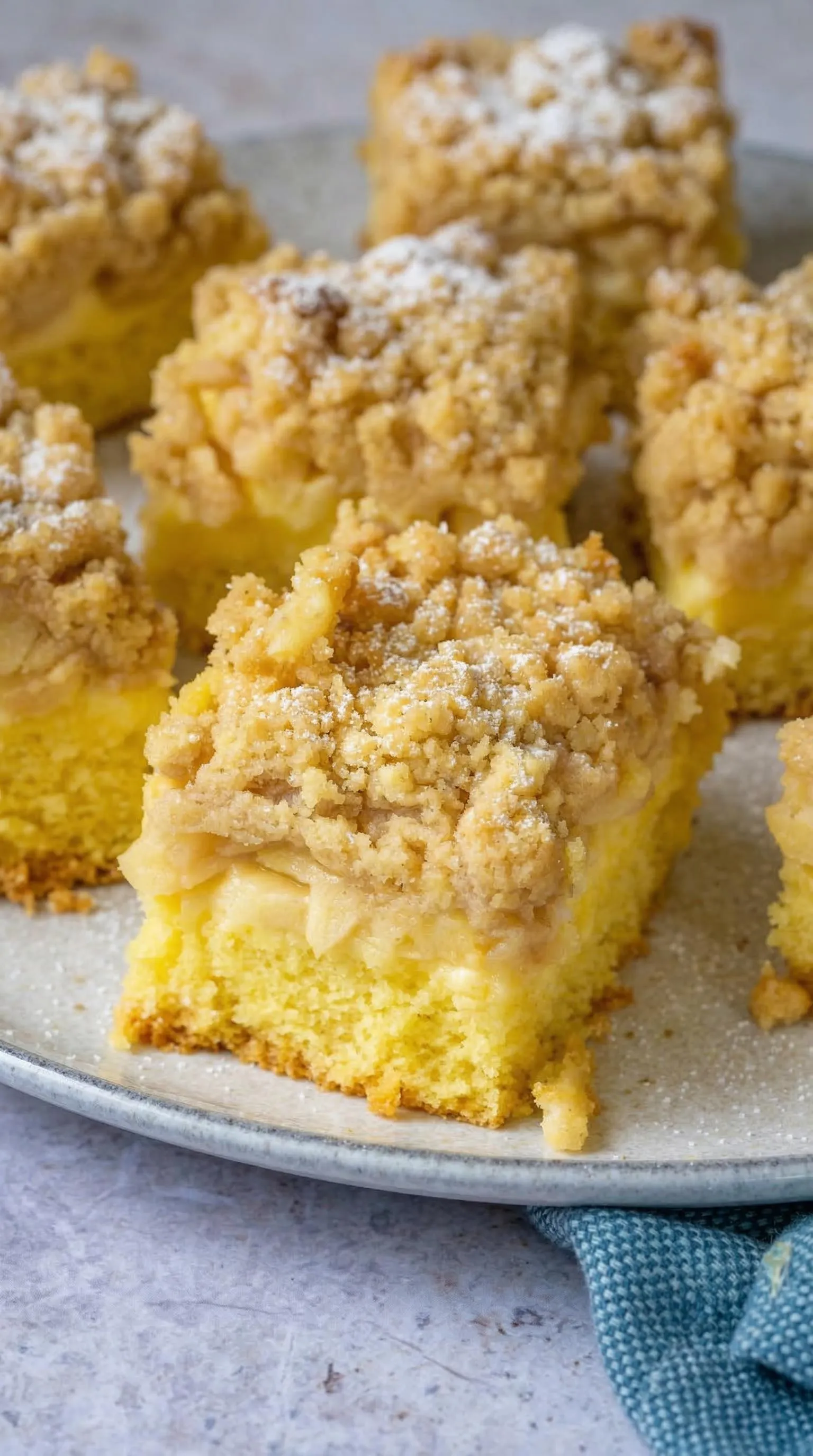 Eine Platte mit Apfelkuchen, die mit Vanillepudding und Streuseln garniert sind.