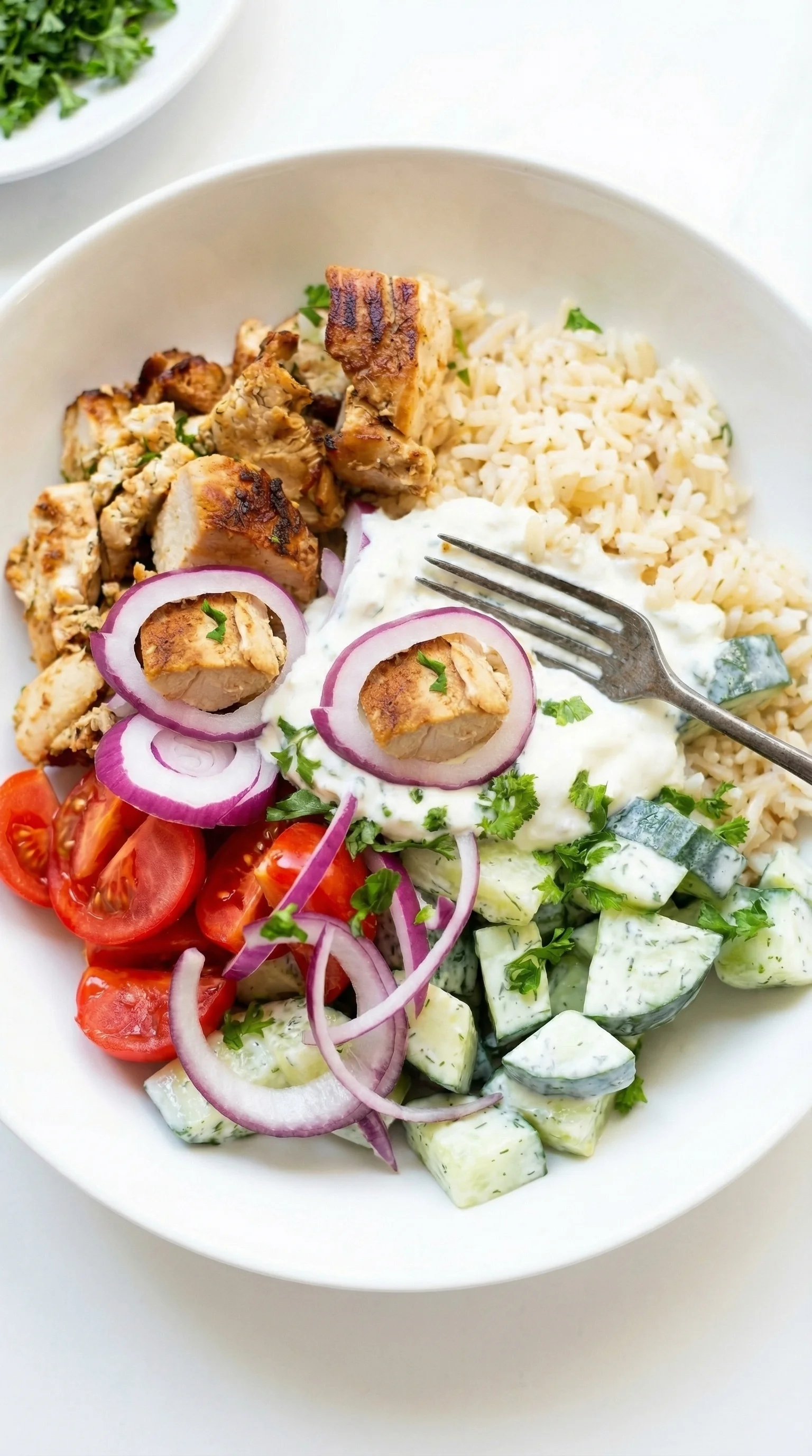 Eine Griechische Hähnchen-Tzatziki Bowl mit verschiedenen Zutaten wie Tomaten, Onions, Zwiebeln, Rice und Hähnchen.
