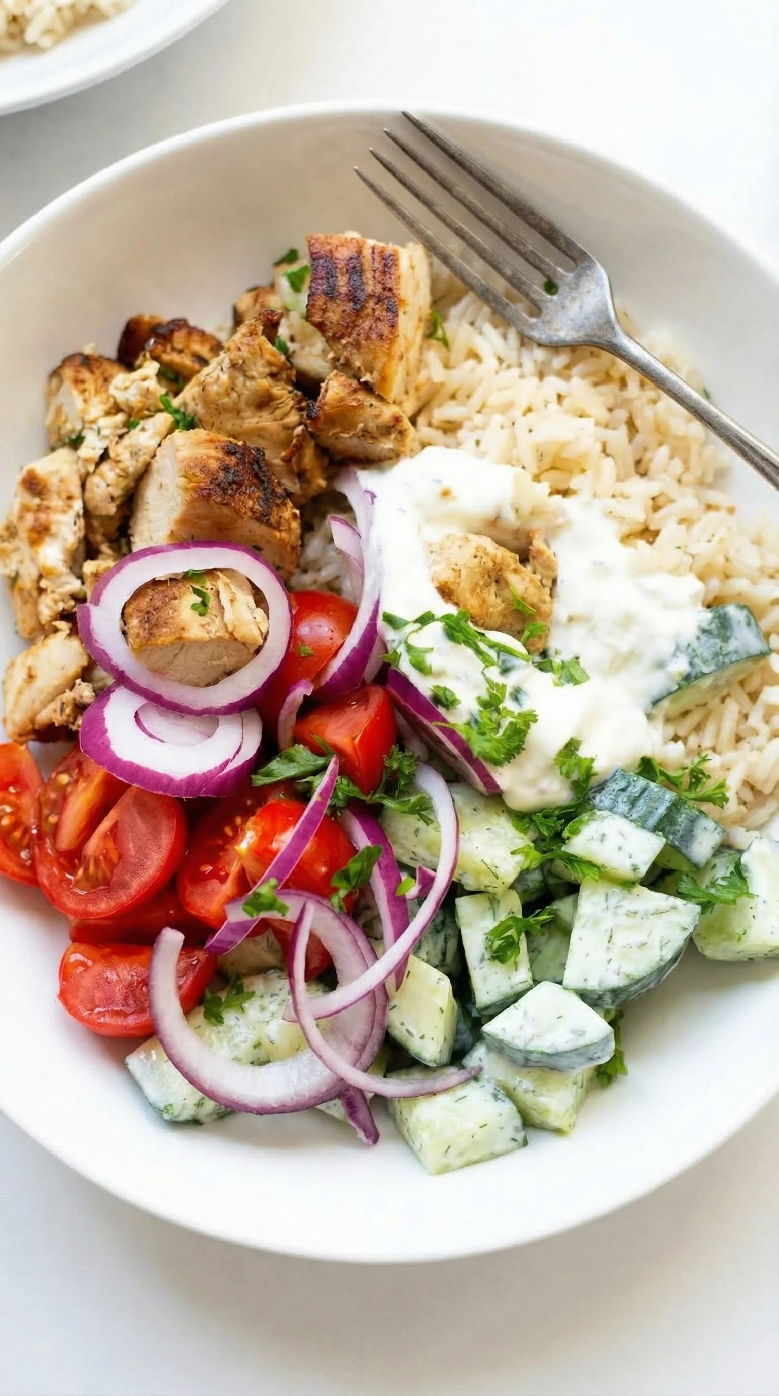 Eine Griechische Hähnchen-Tzatziki Bowl mit verschiedenen Gemüse und Zutaten.