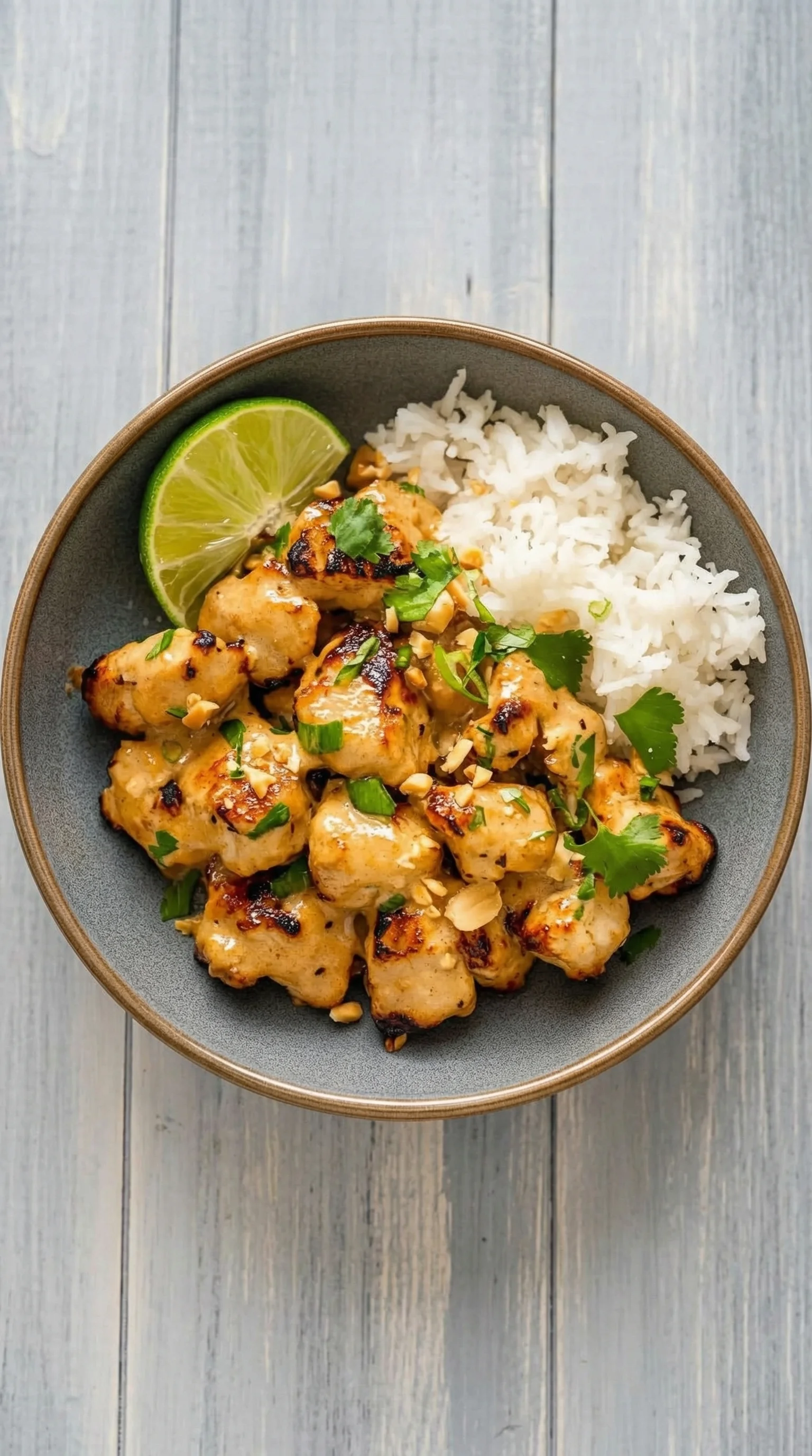 Ein Schüssel mit Thailändisches Erdnuss-Hühnchen, Rice und Lime.