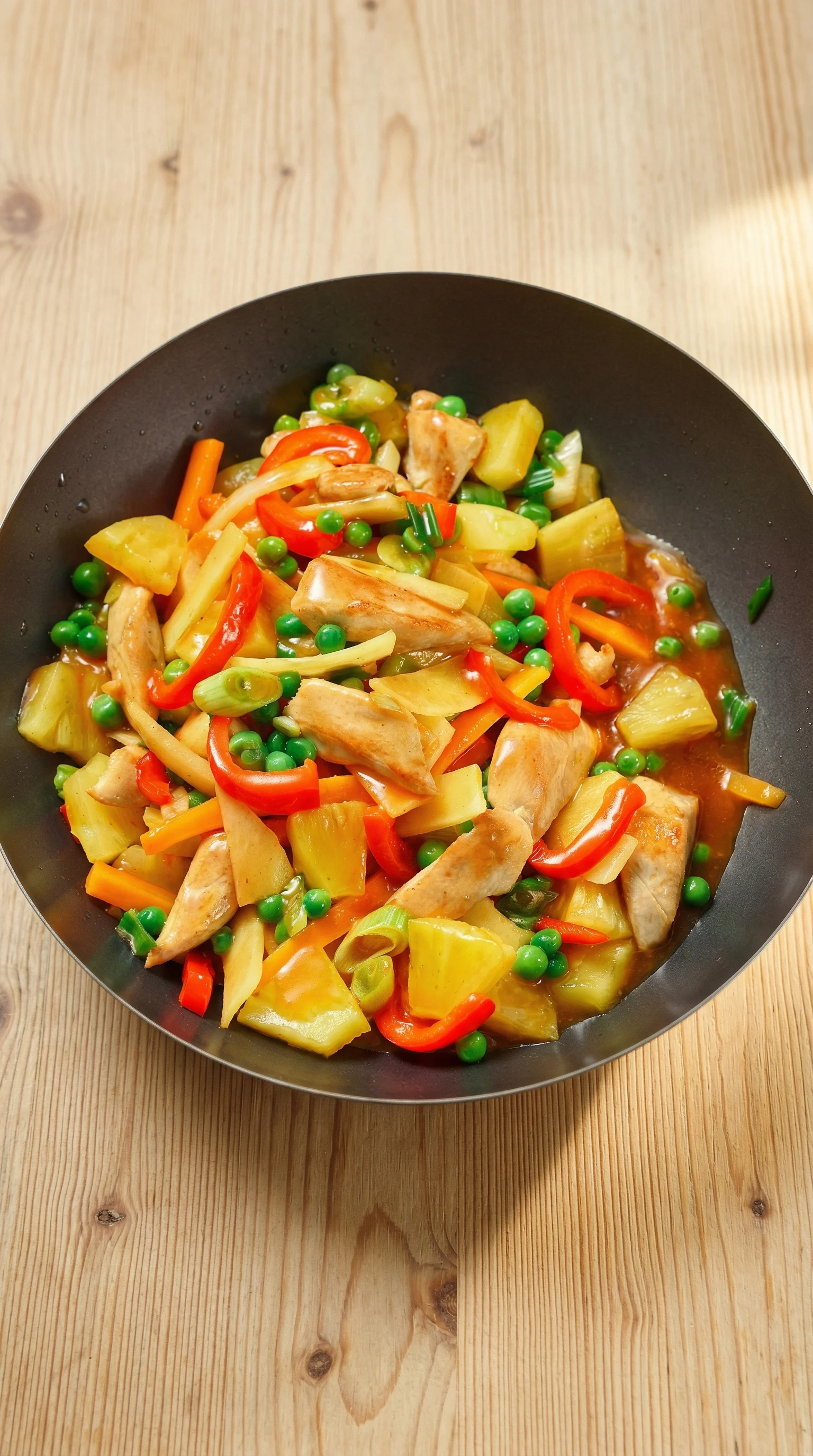Ein Wok mit Hähnchen und Ananas.