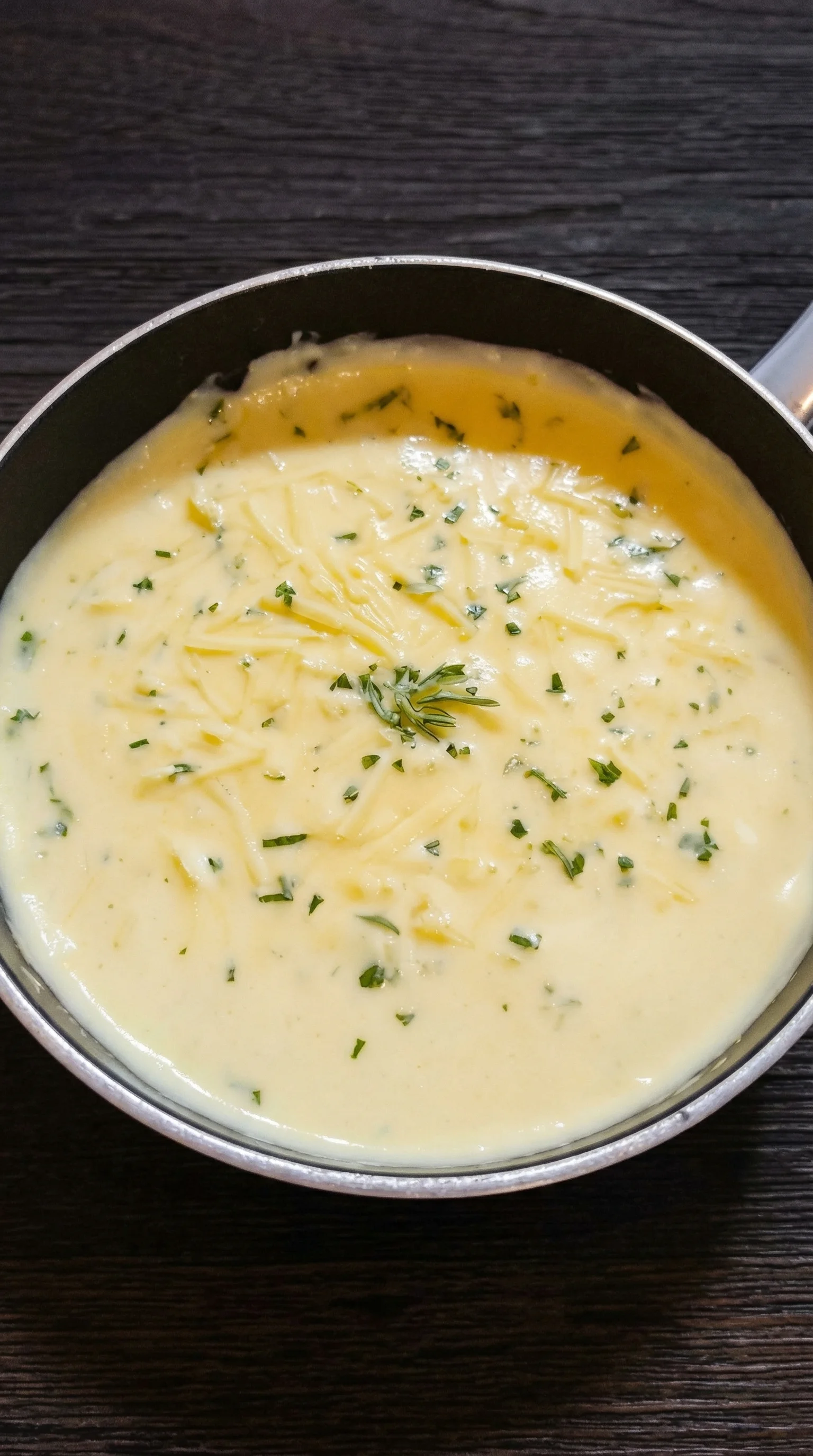 Eine Schüssel mit cremiger Käsesoße, die mit Parsley garniert ist.