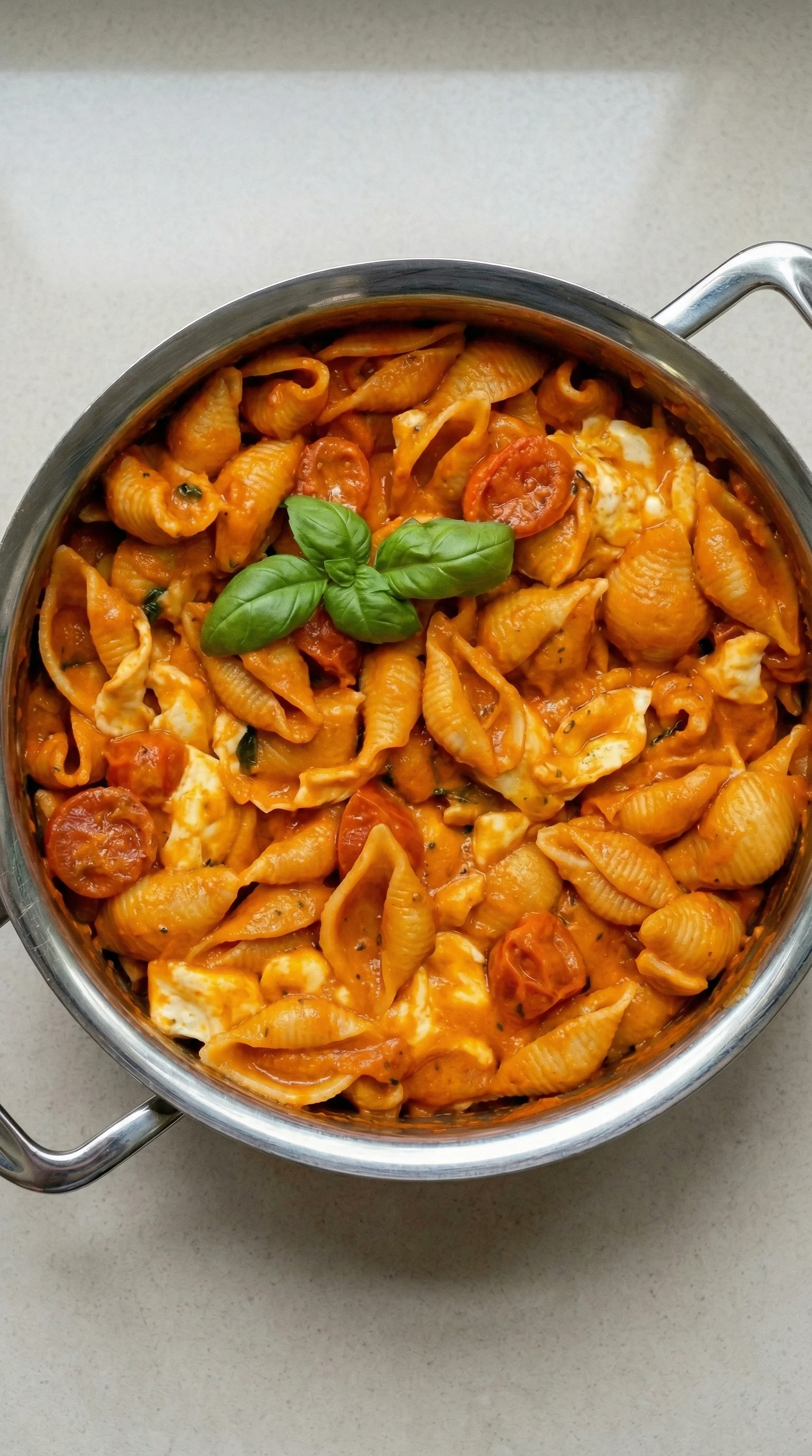 Ein Topf mit Pasta, Tomaten, Mozzarella und Basilikum.