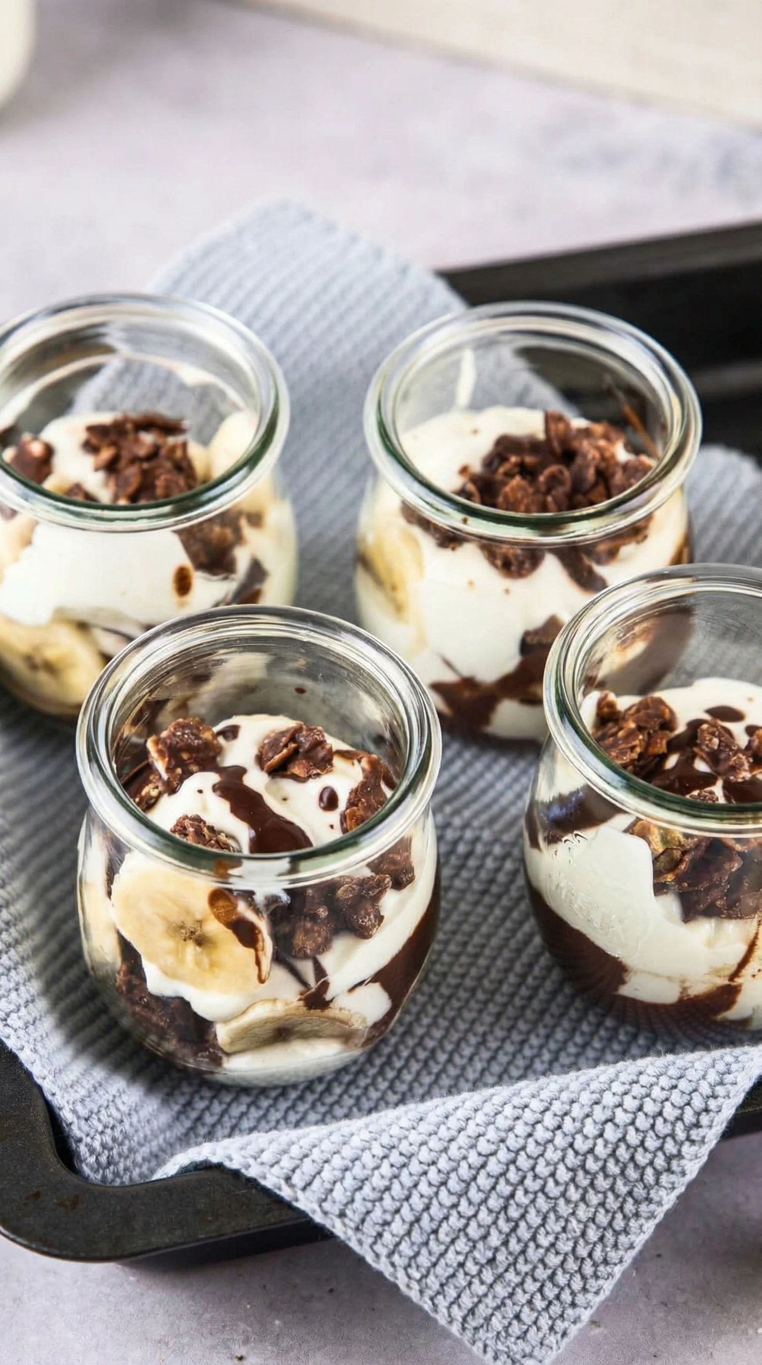 Ein Bananensplit in einer Gläser mit Schokoladenglasur, Bananen, Eis und Walnuss.
