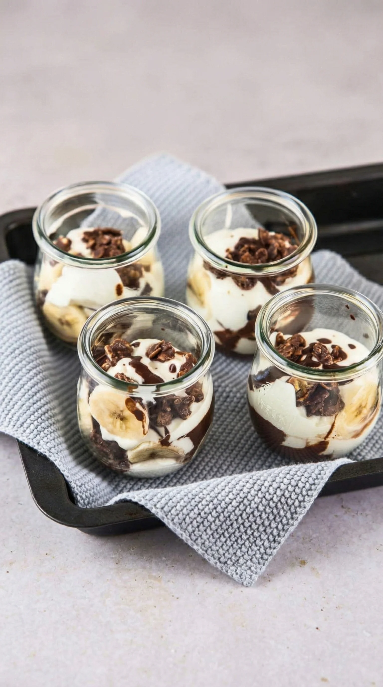 Ein Bananensplit in einem Glas mit Schokoladenglasur, Bananen und Eis.