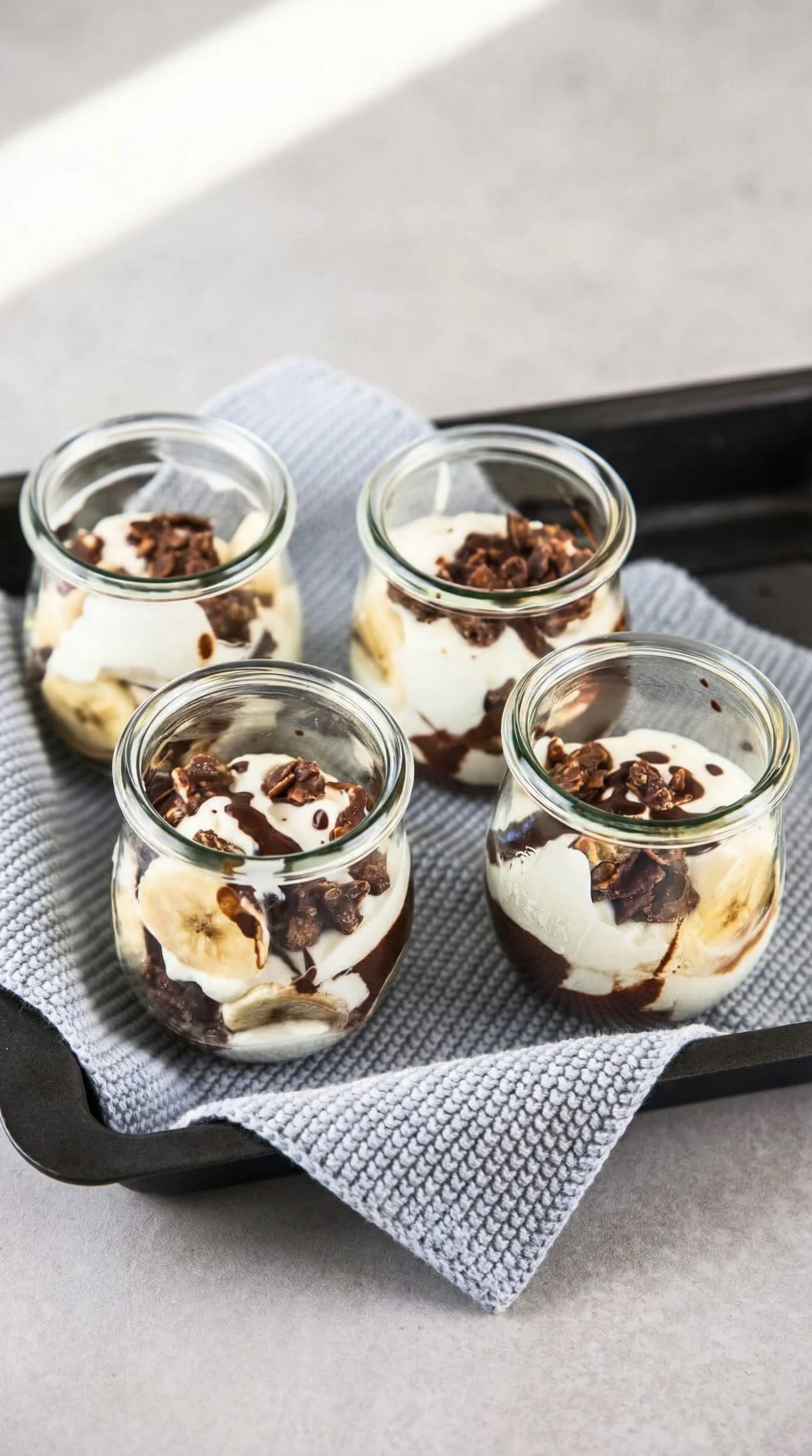 Ein Bananensplit in einem Glas mit Schokoladenglasur, Bananen, Eis und Schokolade.