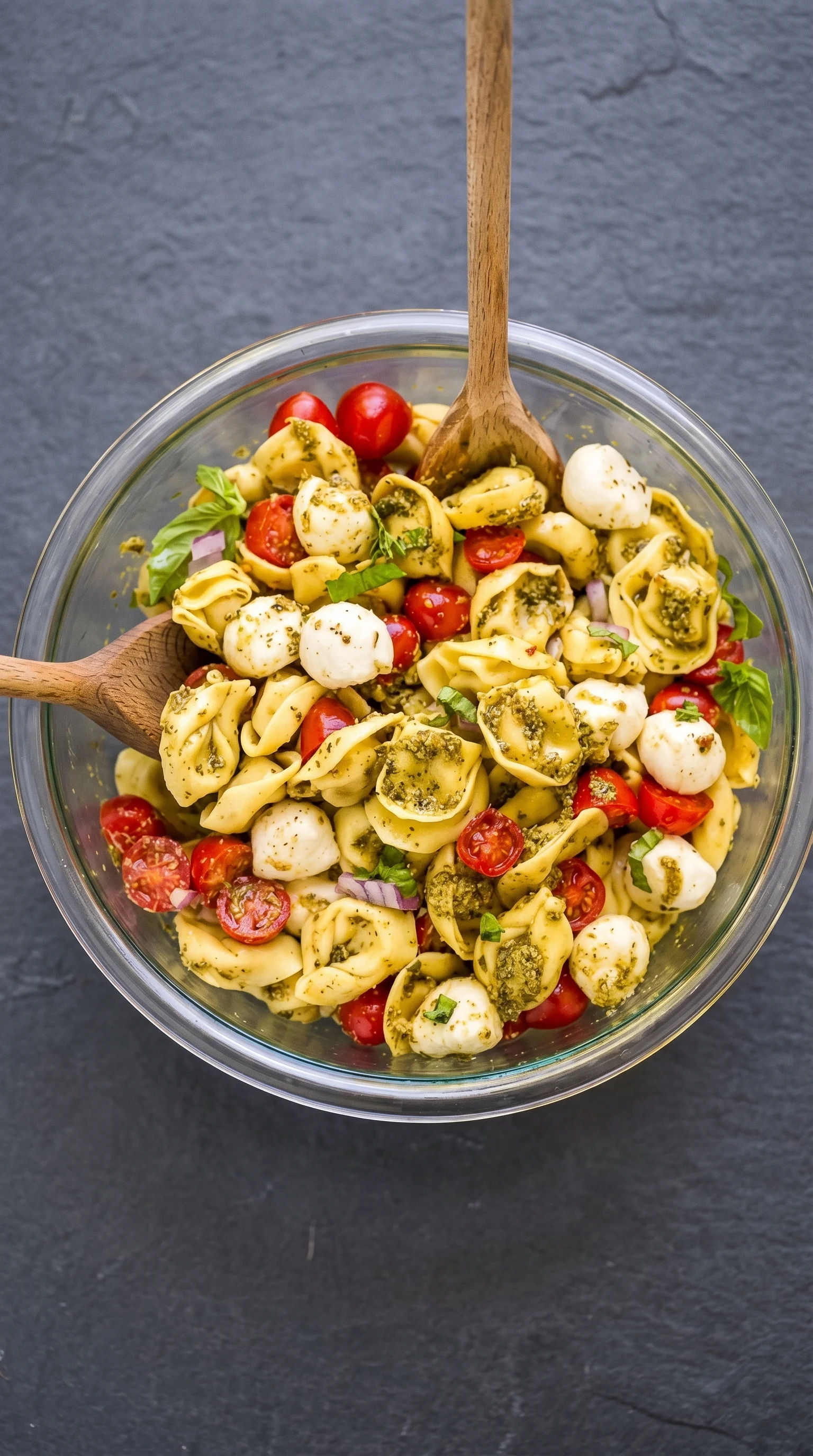 A bowl of pasta salad with tomatoes, basil, and cheese.