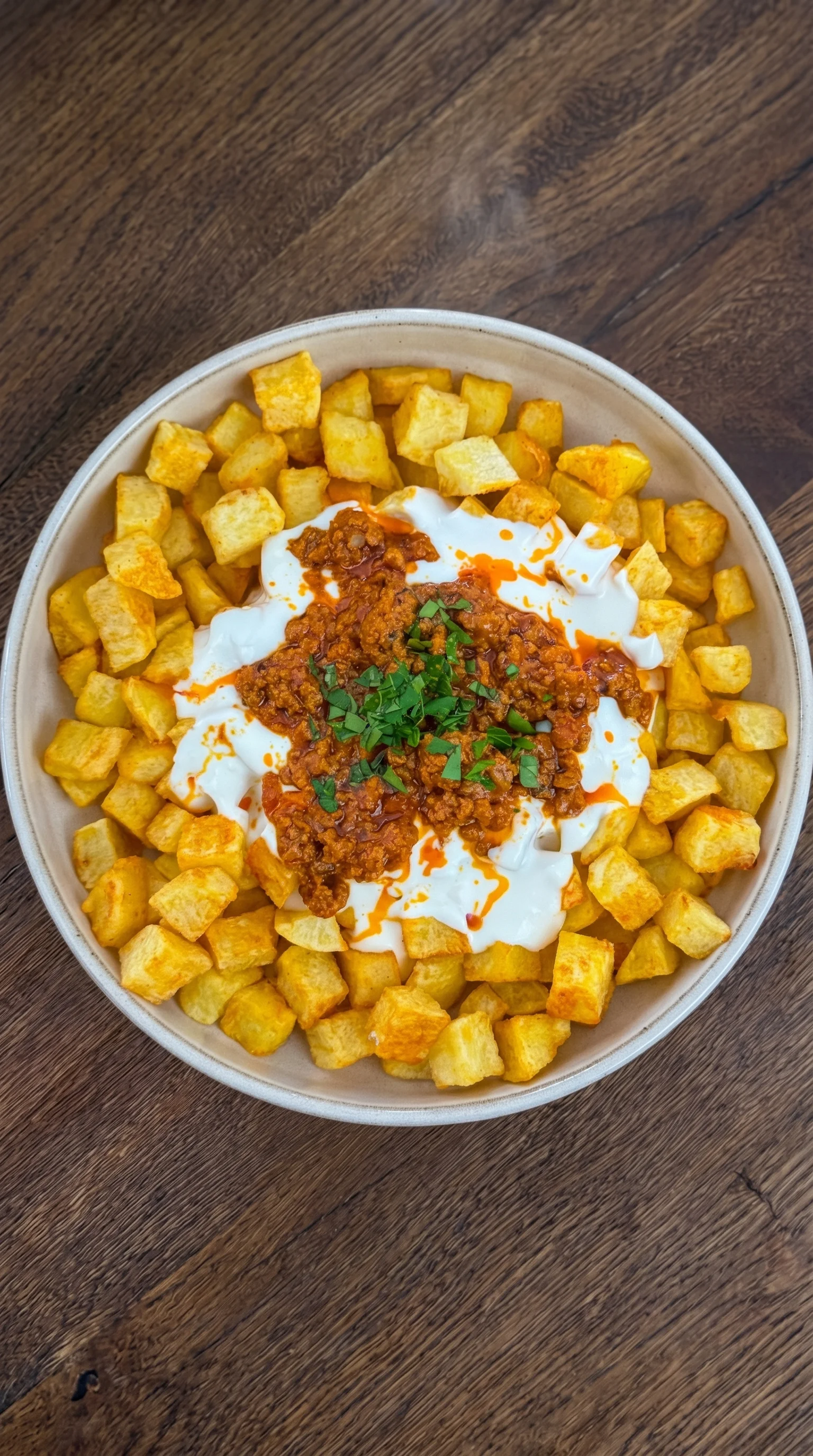 A bowl of food with a white sauce and orange sauce on top.