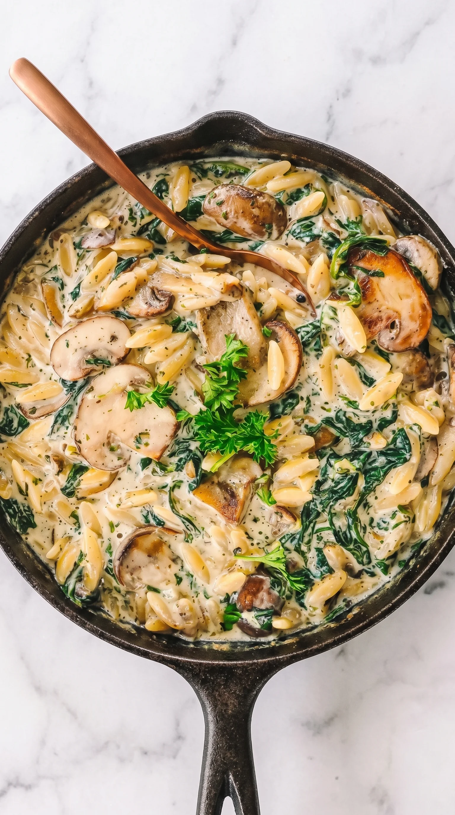 A bowl of creamy orzo with mushrooms and spinach.