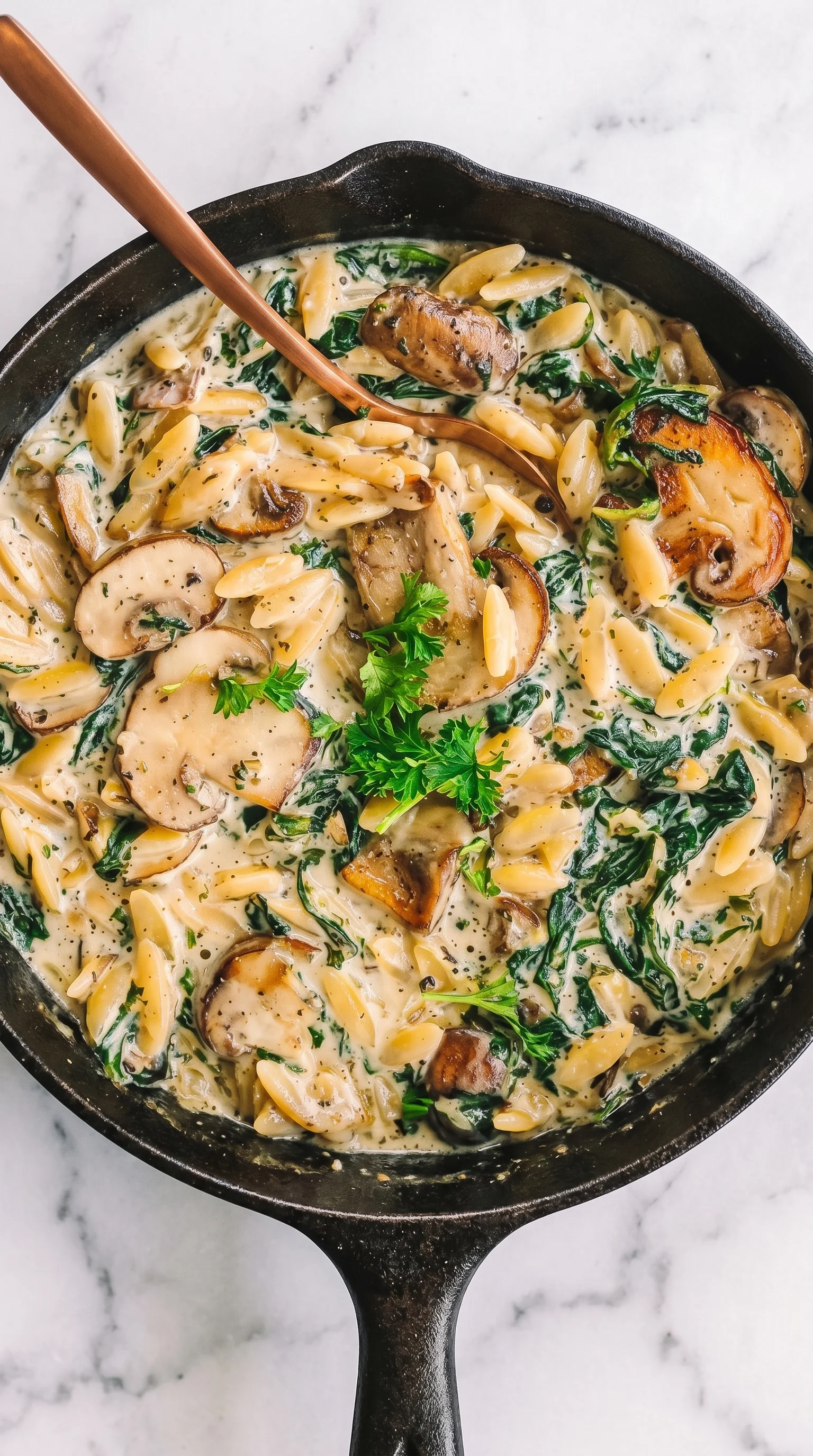 A bowl of creamy orzo with mushrooms and spinach.