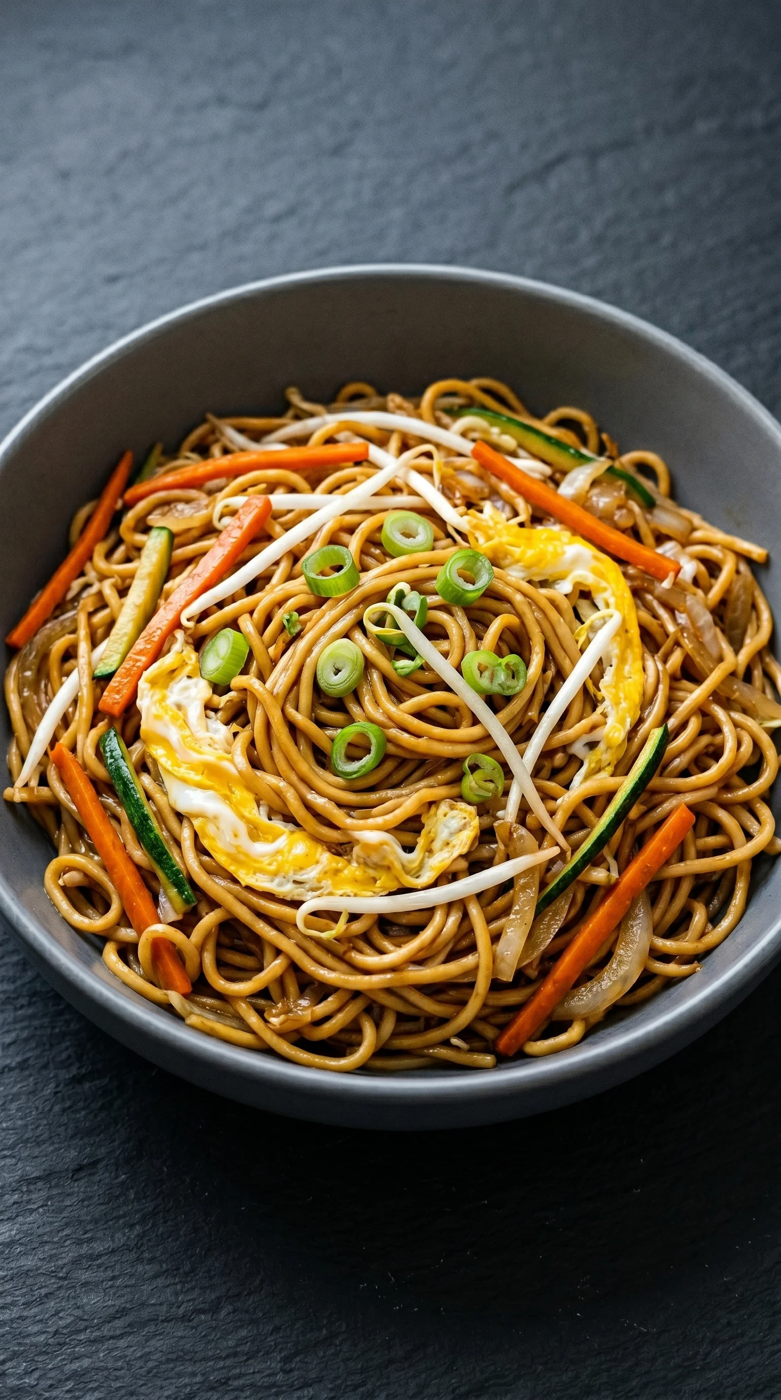 A bowl of noodles with vegetables and egg.