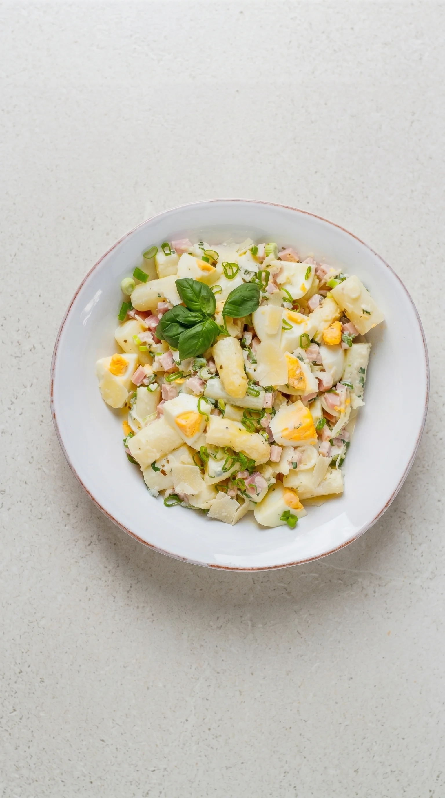 A bowl of pasta salad with eggs and ham.