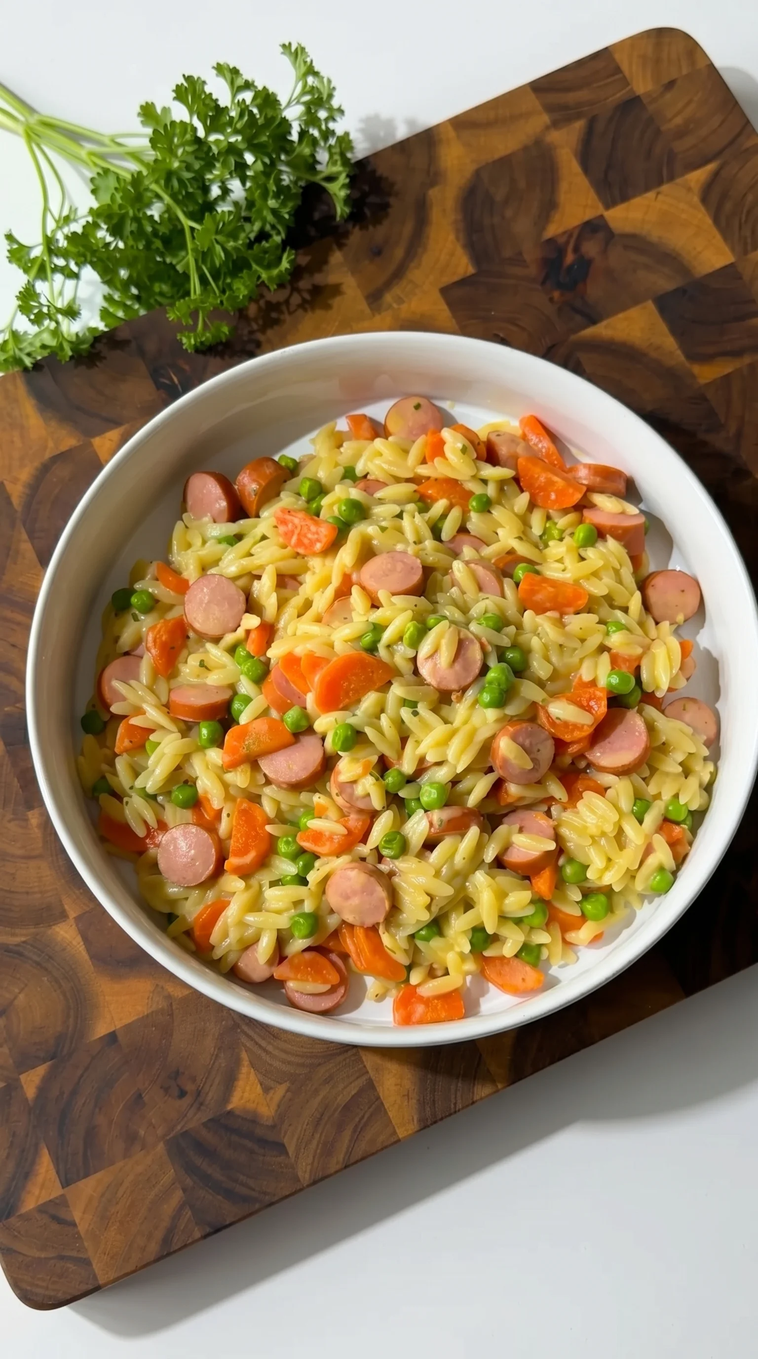 A bowl of pasta with sausage and peas.