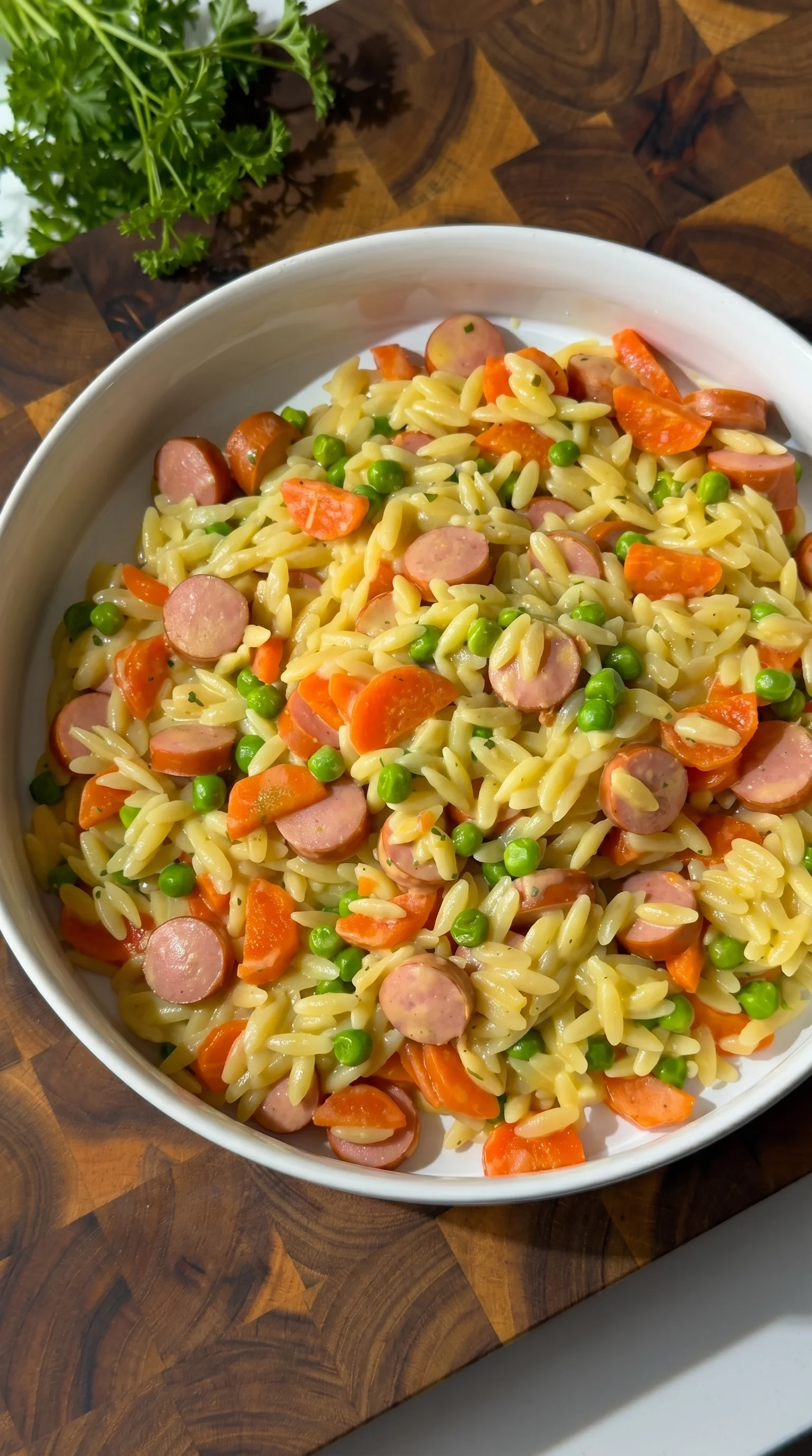 A bowl of pasta with peas and sausage.