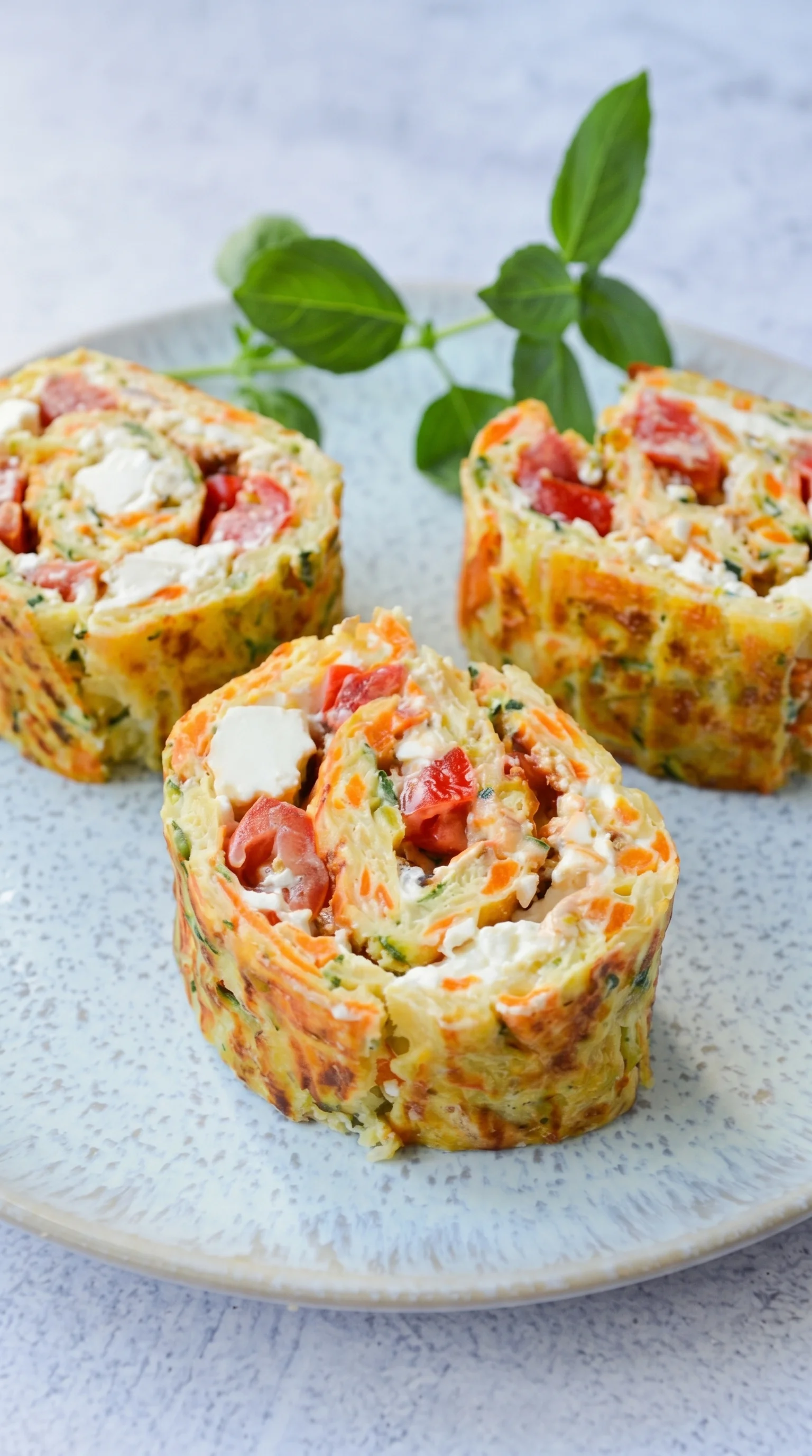 Three vegetable rolls with cheese on a plate.