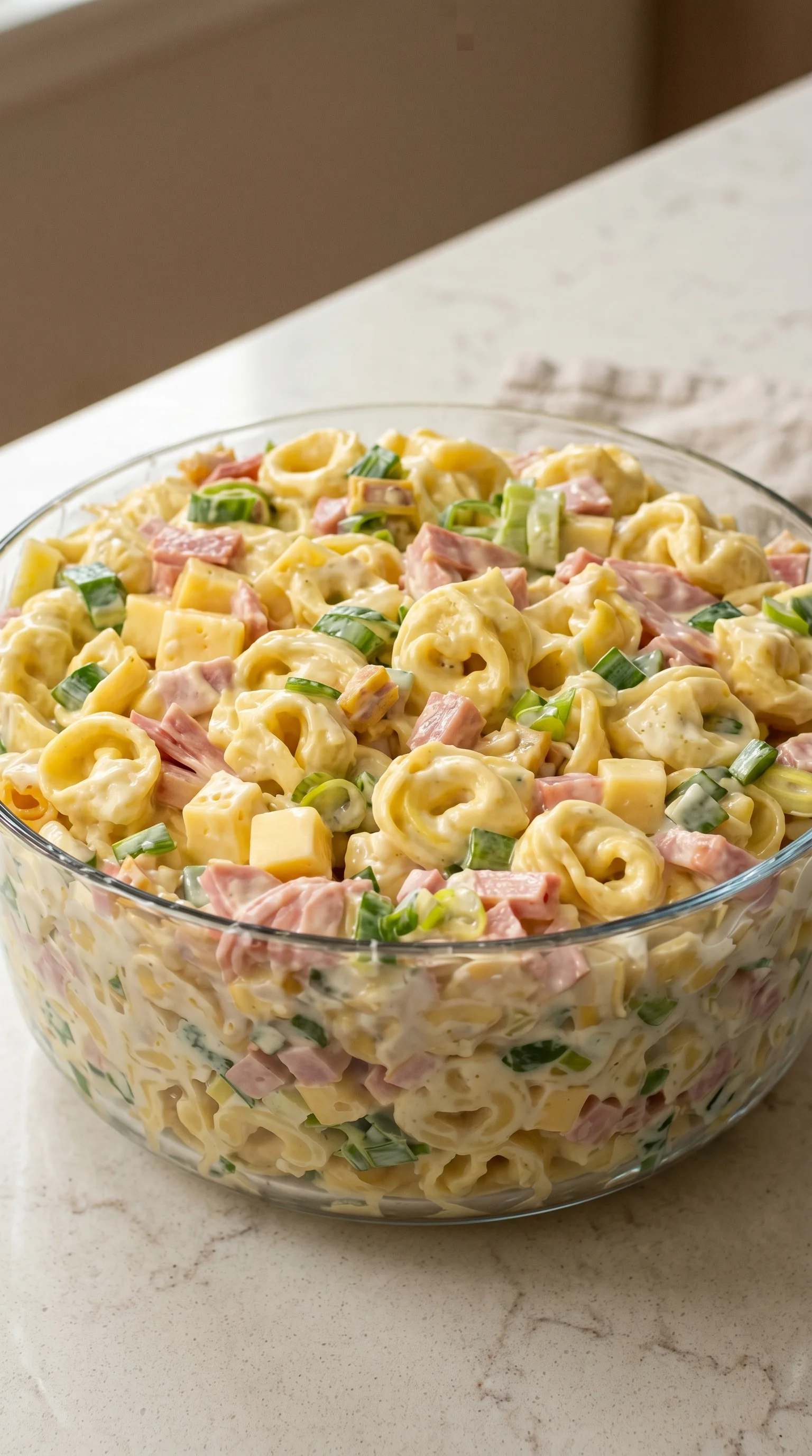 A bowl of pasta salad with ham and cheese.