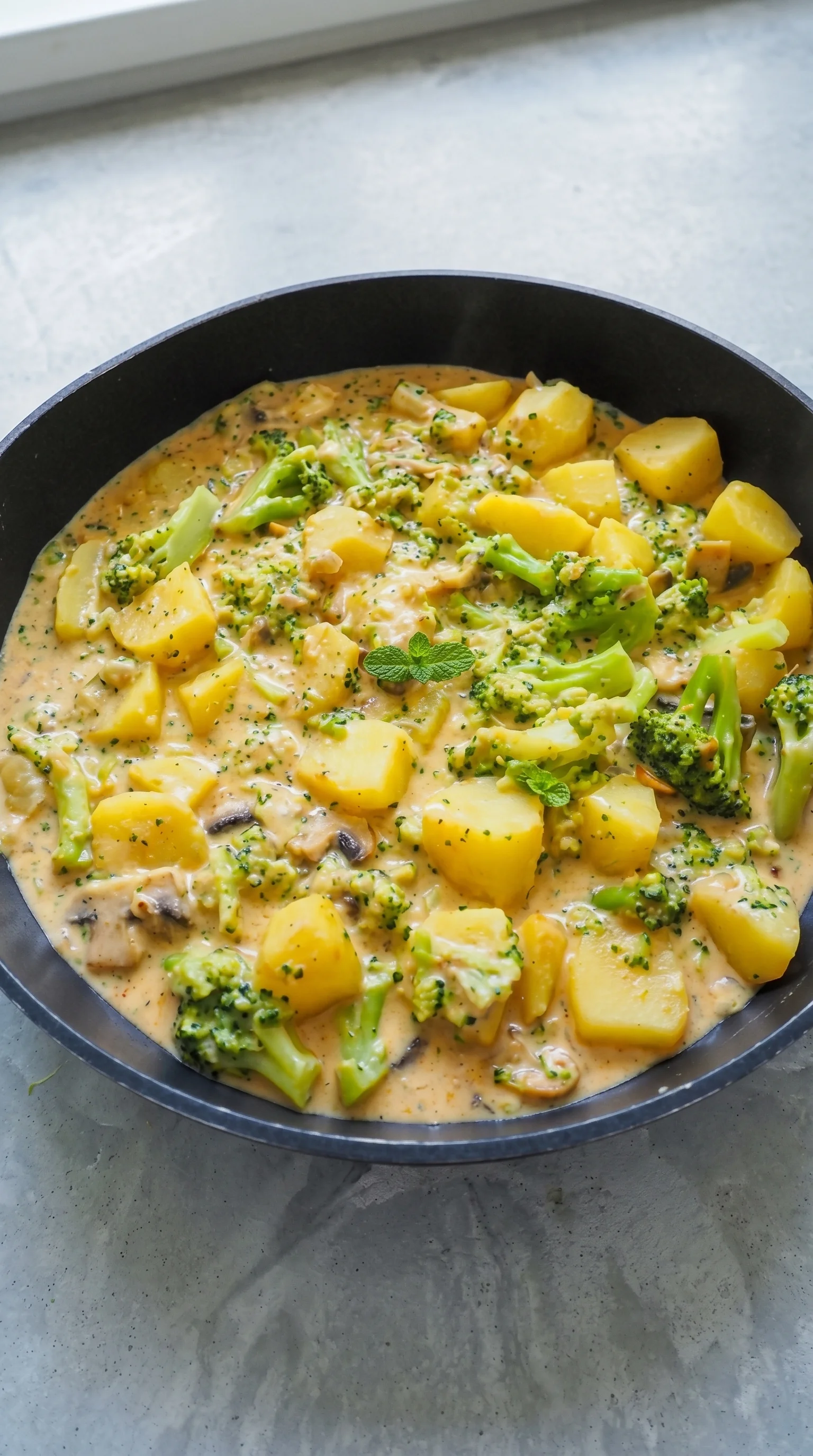 A bowl of food with broccoli and potatoes.