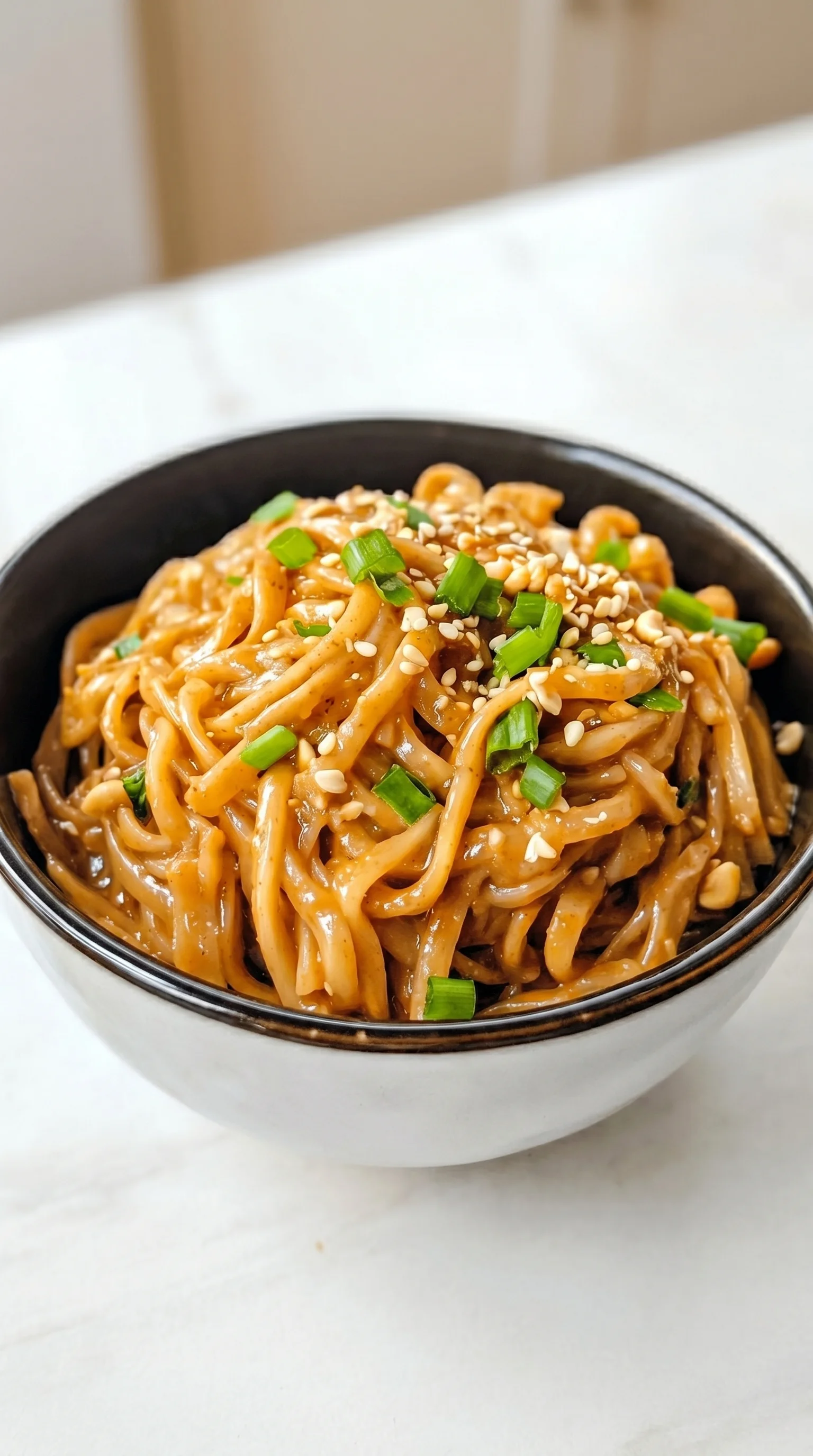 A bowl of noodles with green onions.
