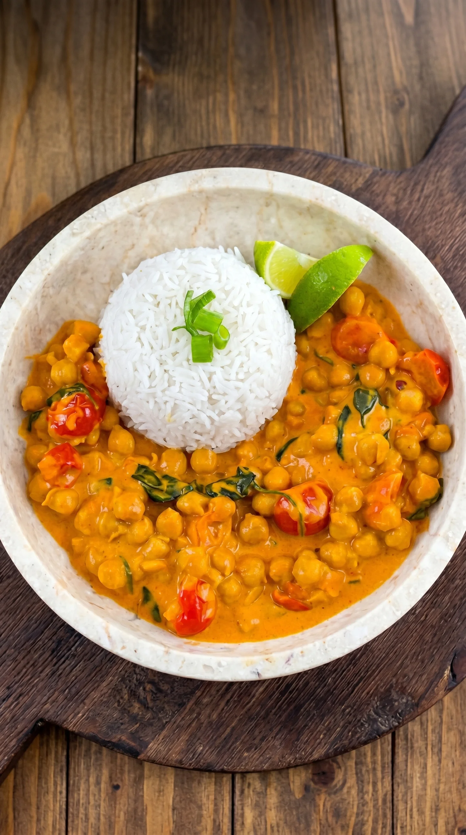 A bowl of curry with rice and lime.