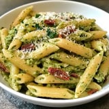 Ein weißer Teller mit Penne-Nudeln und grüner Sauce.