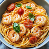 Ein Bogen Spaghetti mit Shrimp, Tomaten und Basilikum.