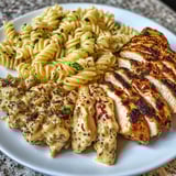 Ein weißer Teller mit Pasta, Käse und Chicken.