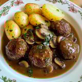 Ein weißer Teller mit einer Mischung aus Fleisch, Gemüse und Kartoffeln.
