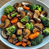 Ein weißer Teller mit einer Mischung aus Mushrooms, Broccoli und Karotten.