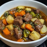 Ein weißer Teller mit einer Mischung aus Fleisch, Gemüse und Kartoffeln.