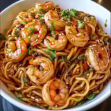 Ein weißer Teller mit einer Mischung aus Shrimp, Sesam und Noodles.